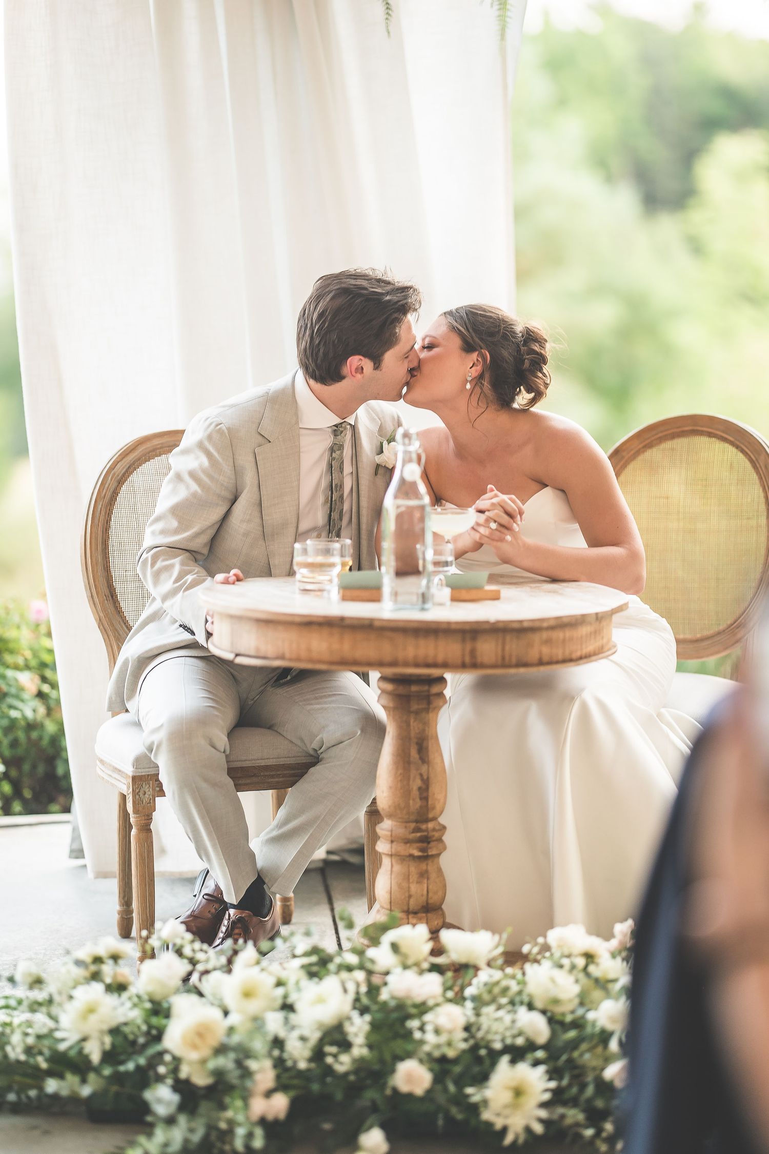Intimate moment between newlyweds at an elegantly set table with floral decorations.