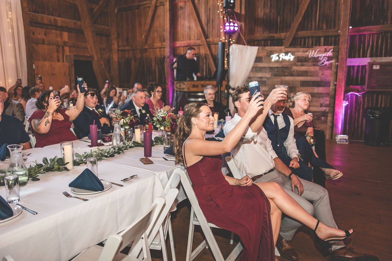 Wedding guests dance and celebrate on a rustic wooden dance floor during an evening reception.