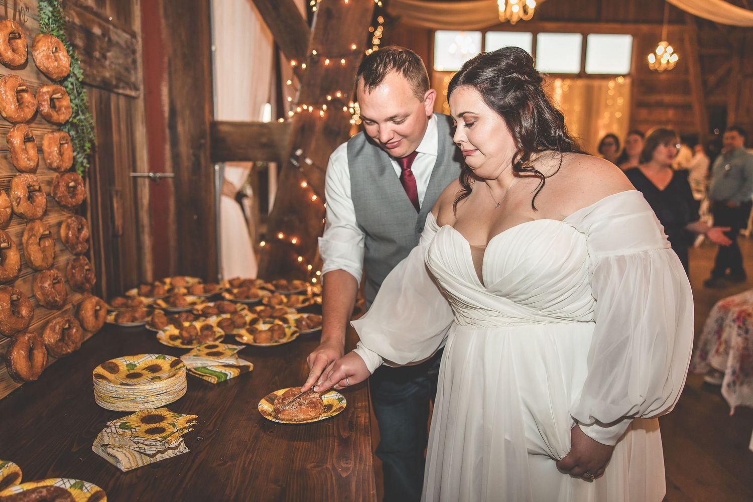 Newlyweds selecting desserts together at their rustic barn wedding reception.