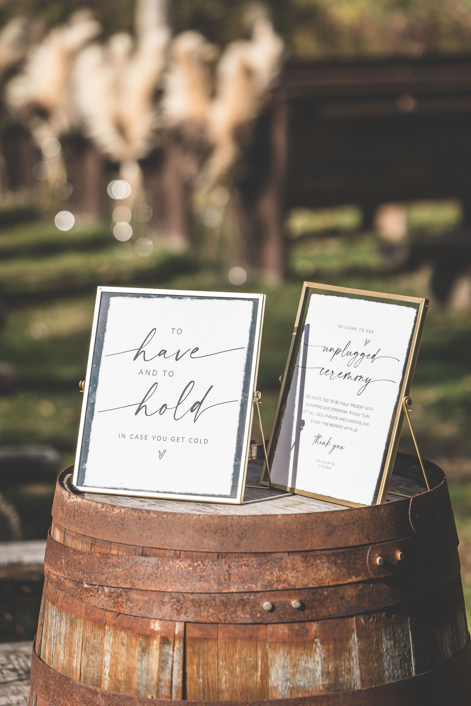Wedding signage displayed on rustic wooden barrels in an outdoor setting.