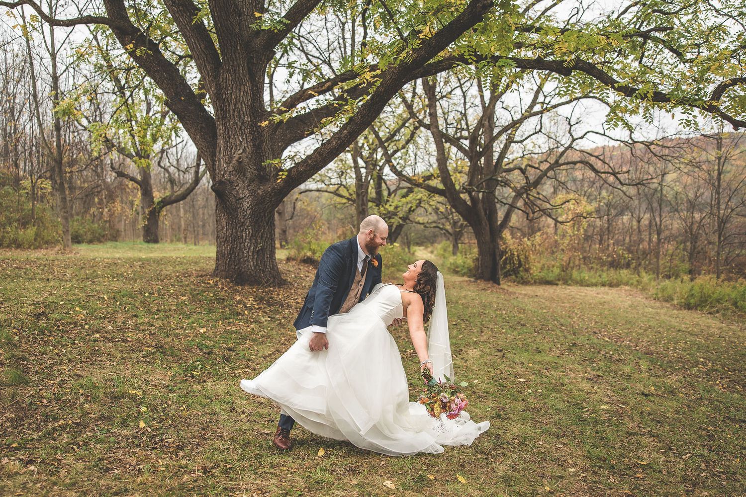 Wedding couple walks through a scenic autumn forest setting during their photoshoot.