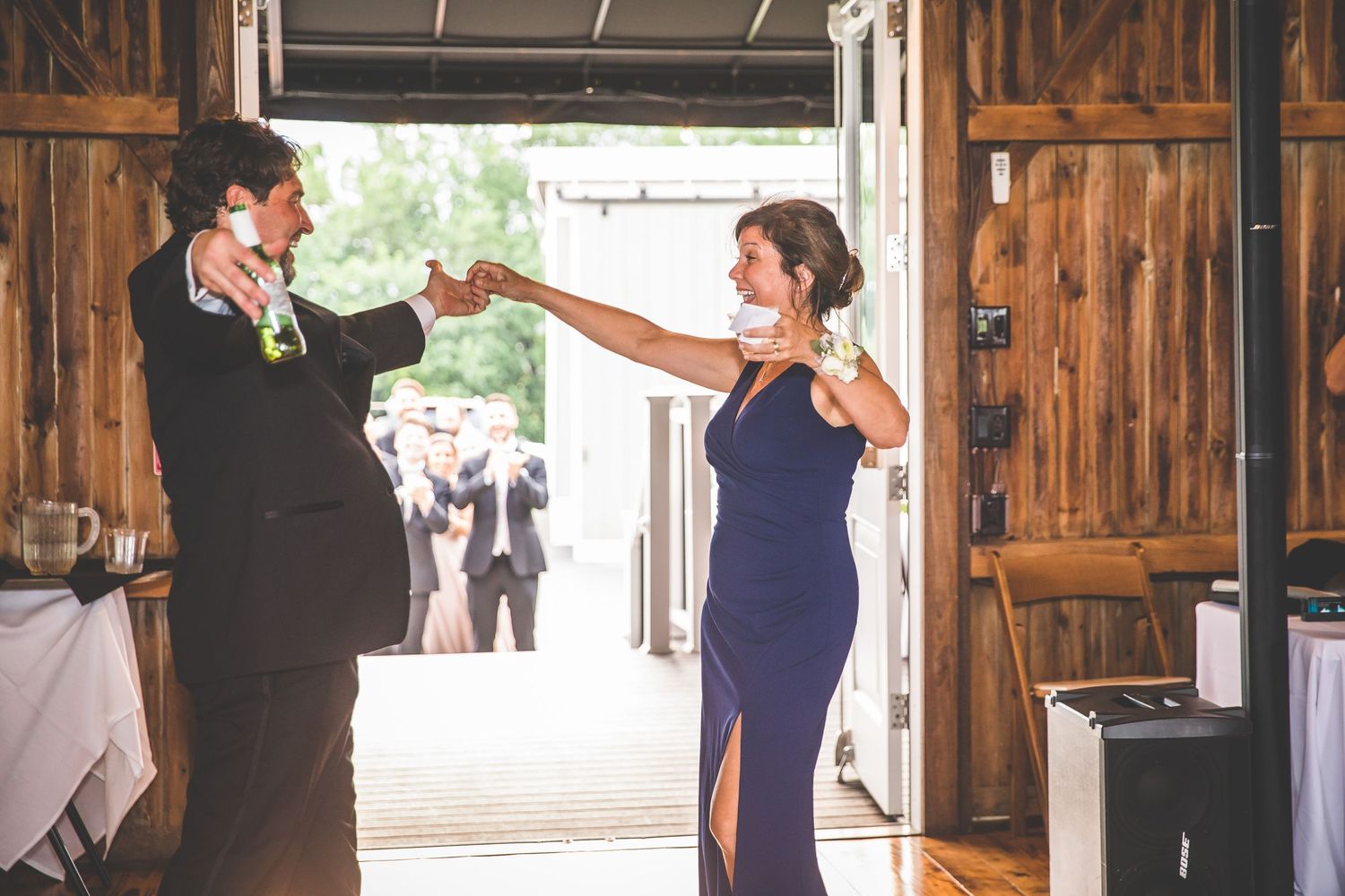 Celebratory dance moment in rustic barn setting with wooden interior.