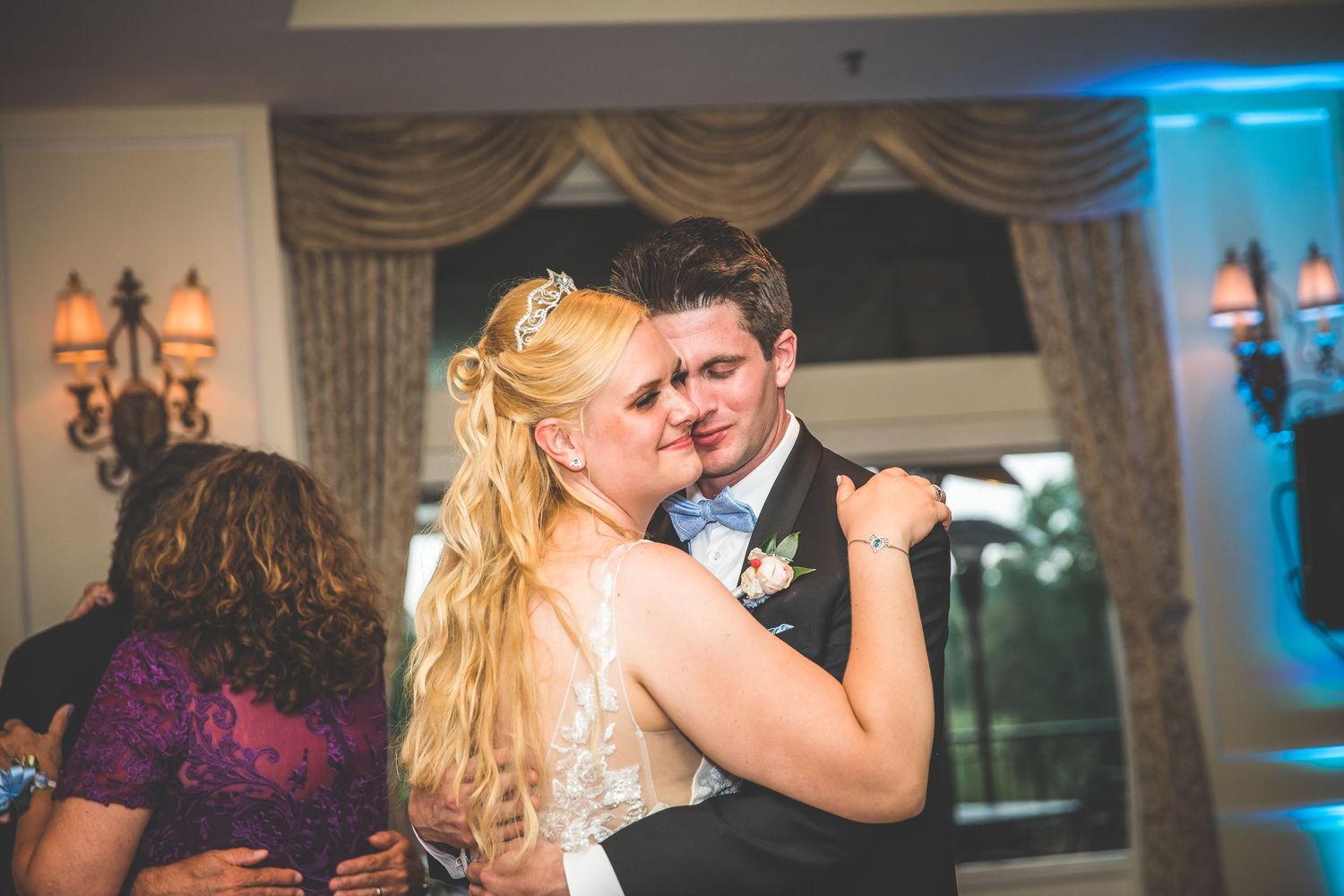 Romantic dance moment at wedding reception with blue accent lighting and elegant decor.