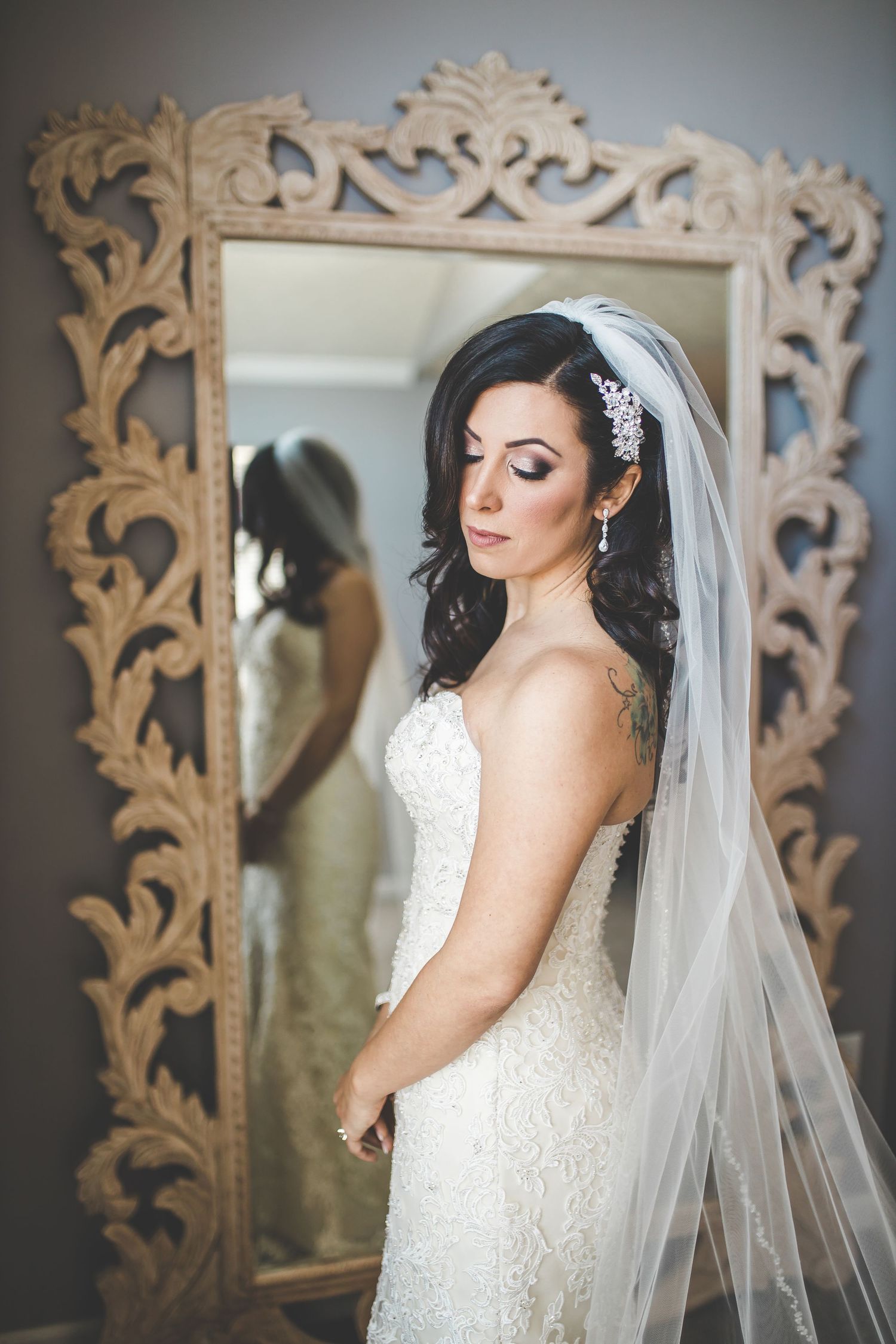 Elegant bridal portrait with ornate white vintage frame backdrop and flowing veil.