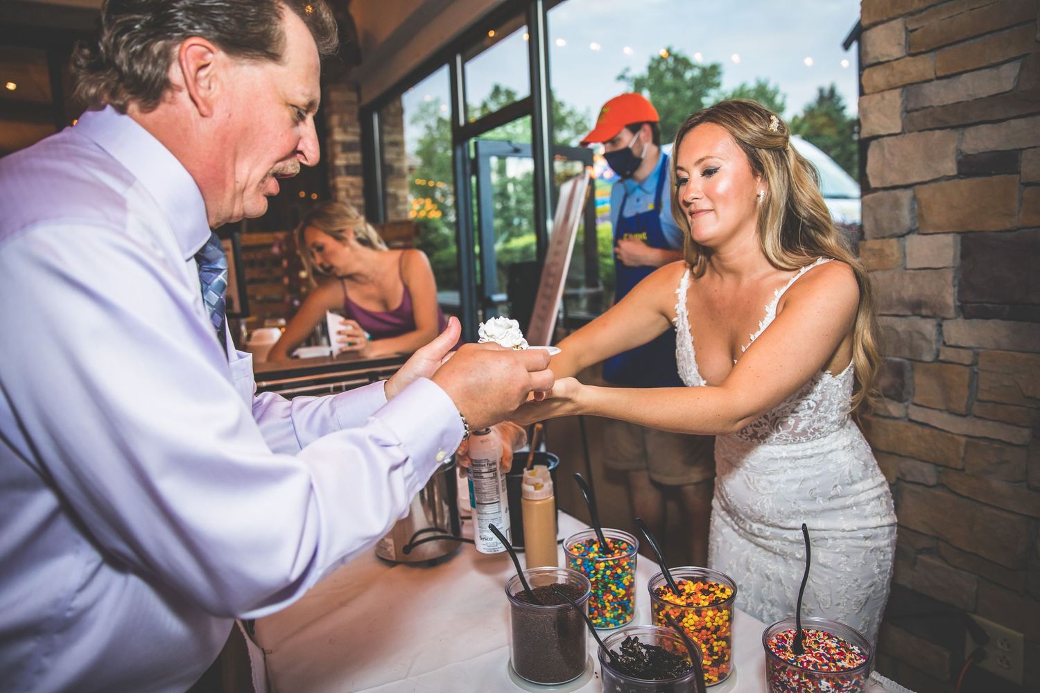 A couple shares a dance moment during their wedding reception near stone pillars.