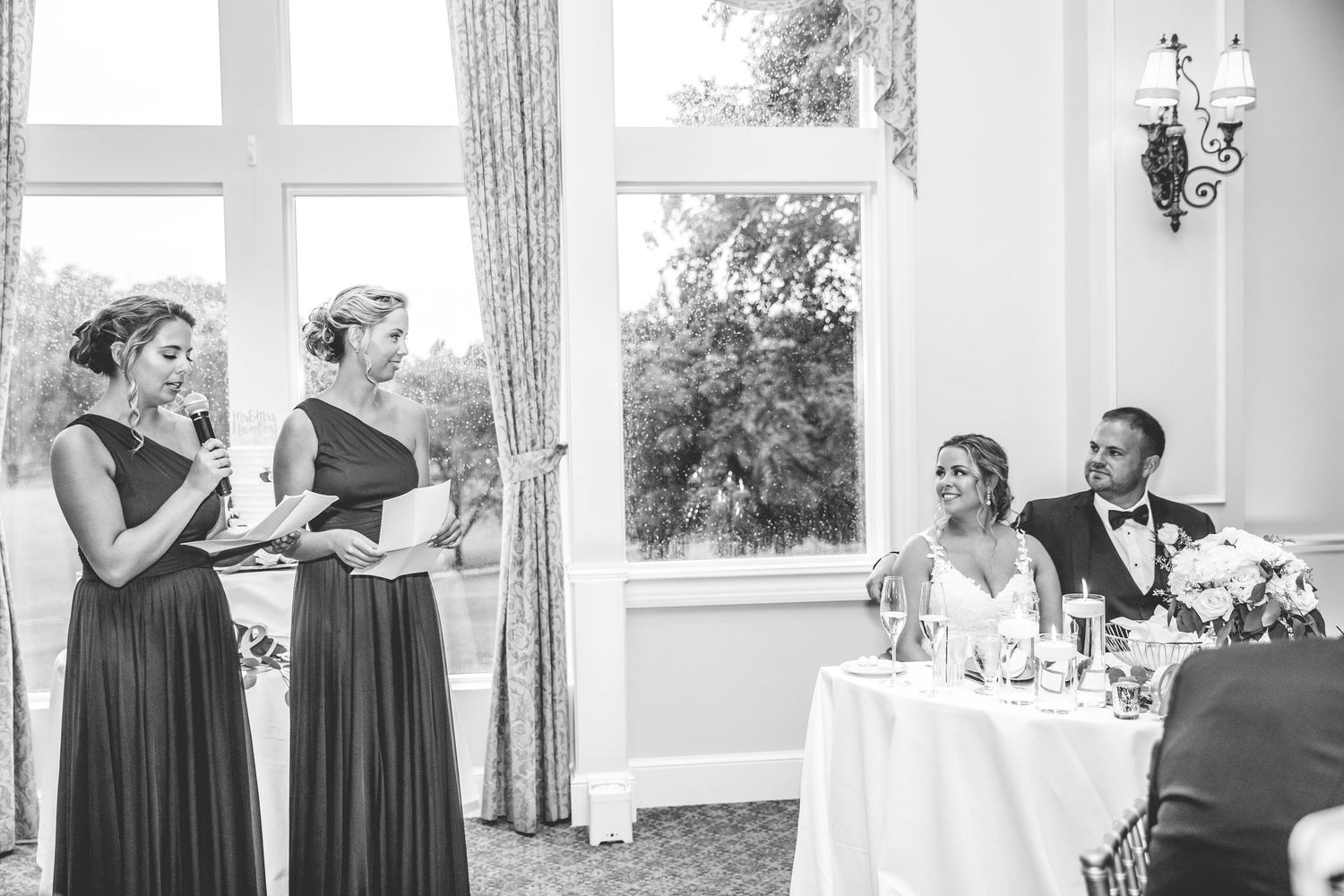Elegant wedding reception hall decorated in white with large windows and crystal chandeliers.