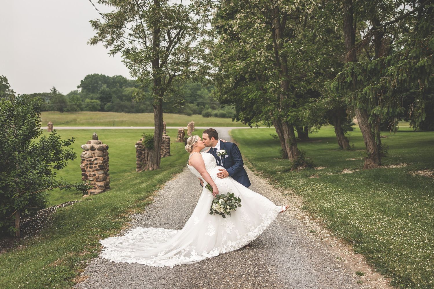 Wedding dress train flowing along curved gravel path in garden setting.