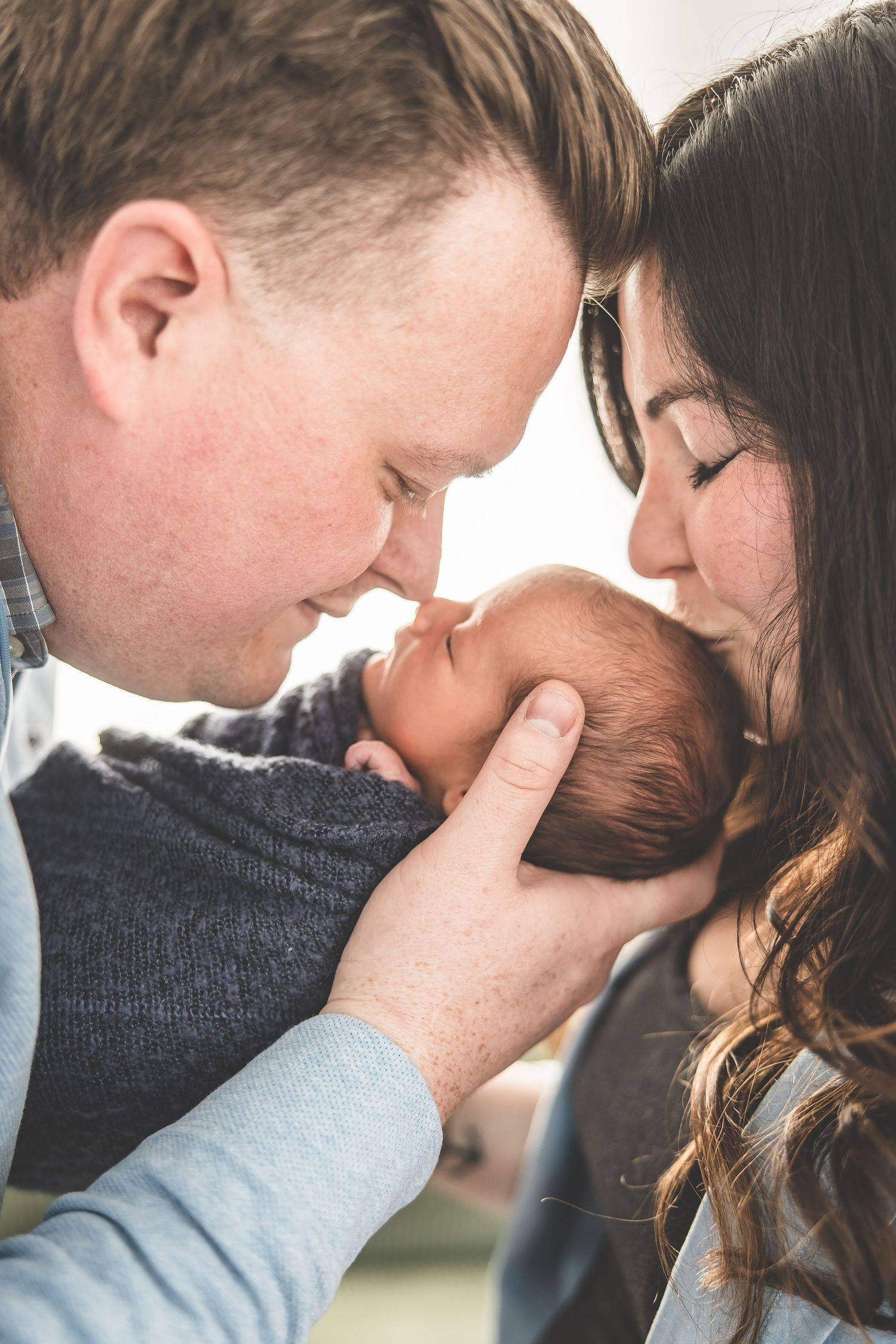 Tender family moment as parents lean in close to their newborn.