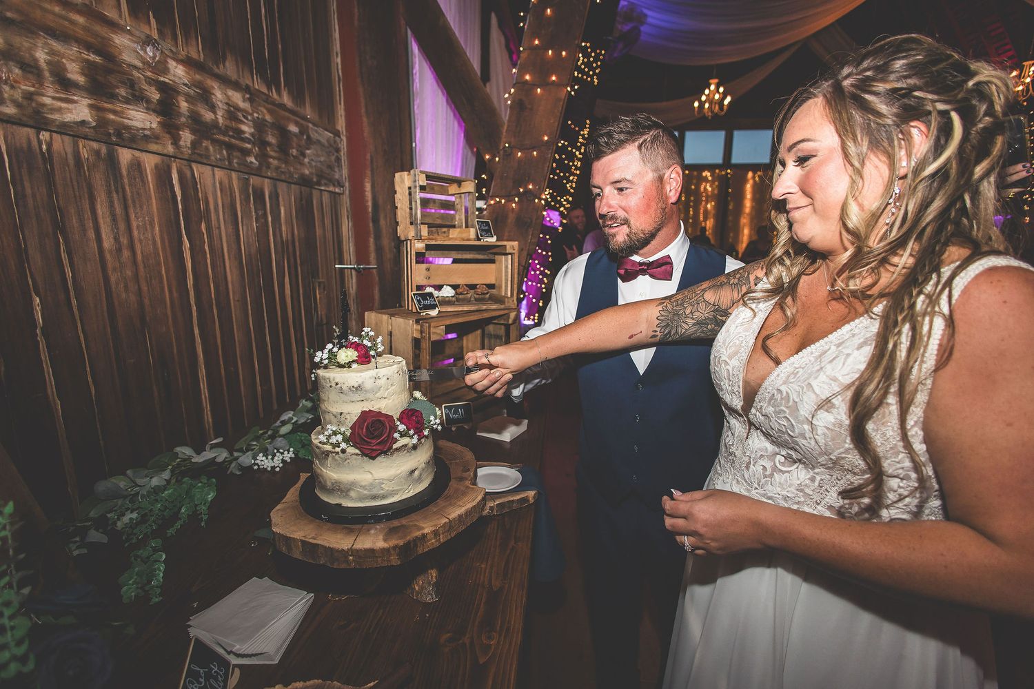 Wedding reception celebration in a rustic barn venue with romantic lighting and decorative elements.