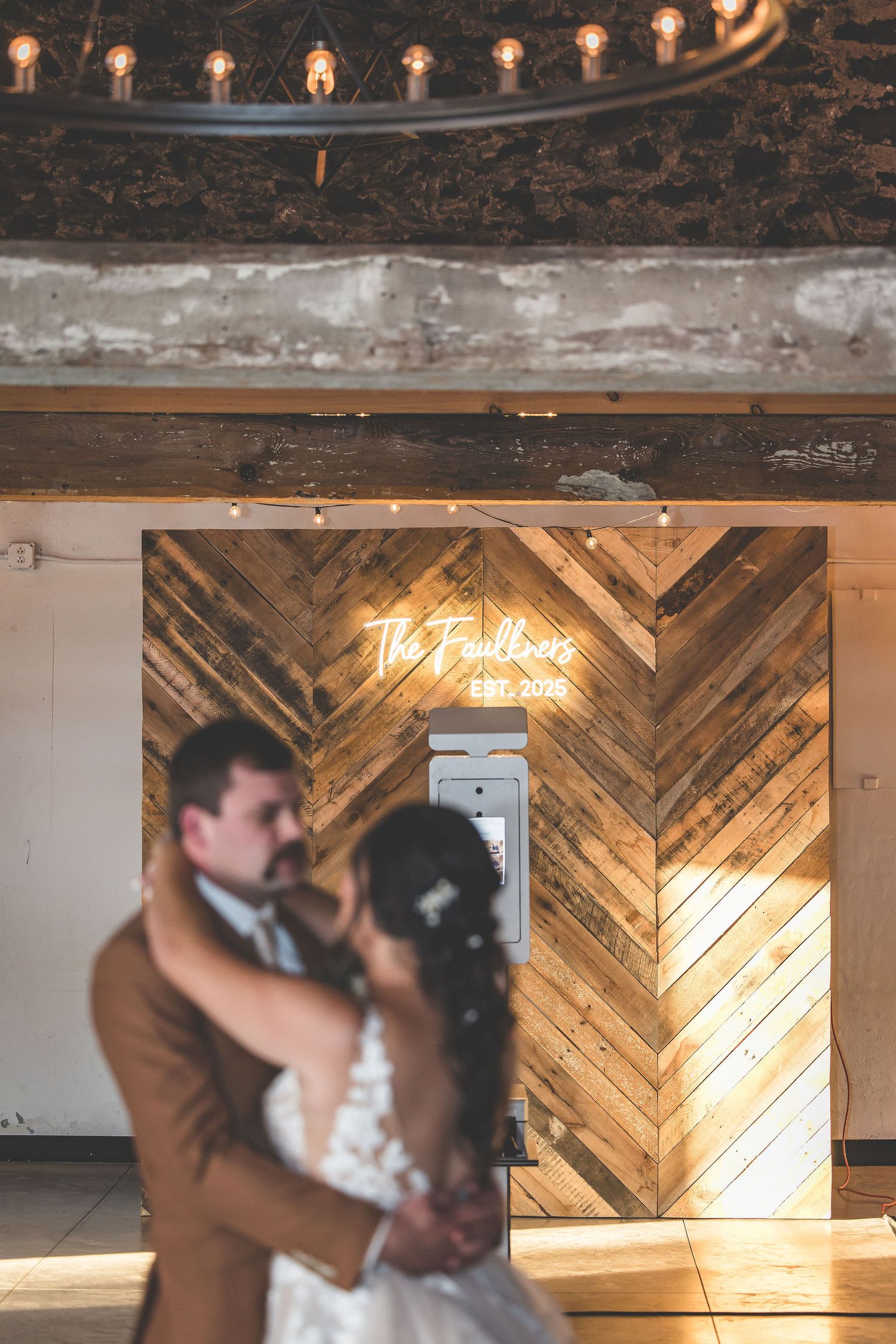 Rustic barn wedding venue with wooden chevron wall panels and romantic string lighting overhead.