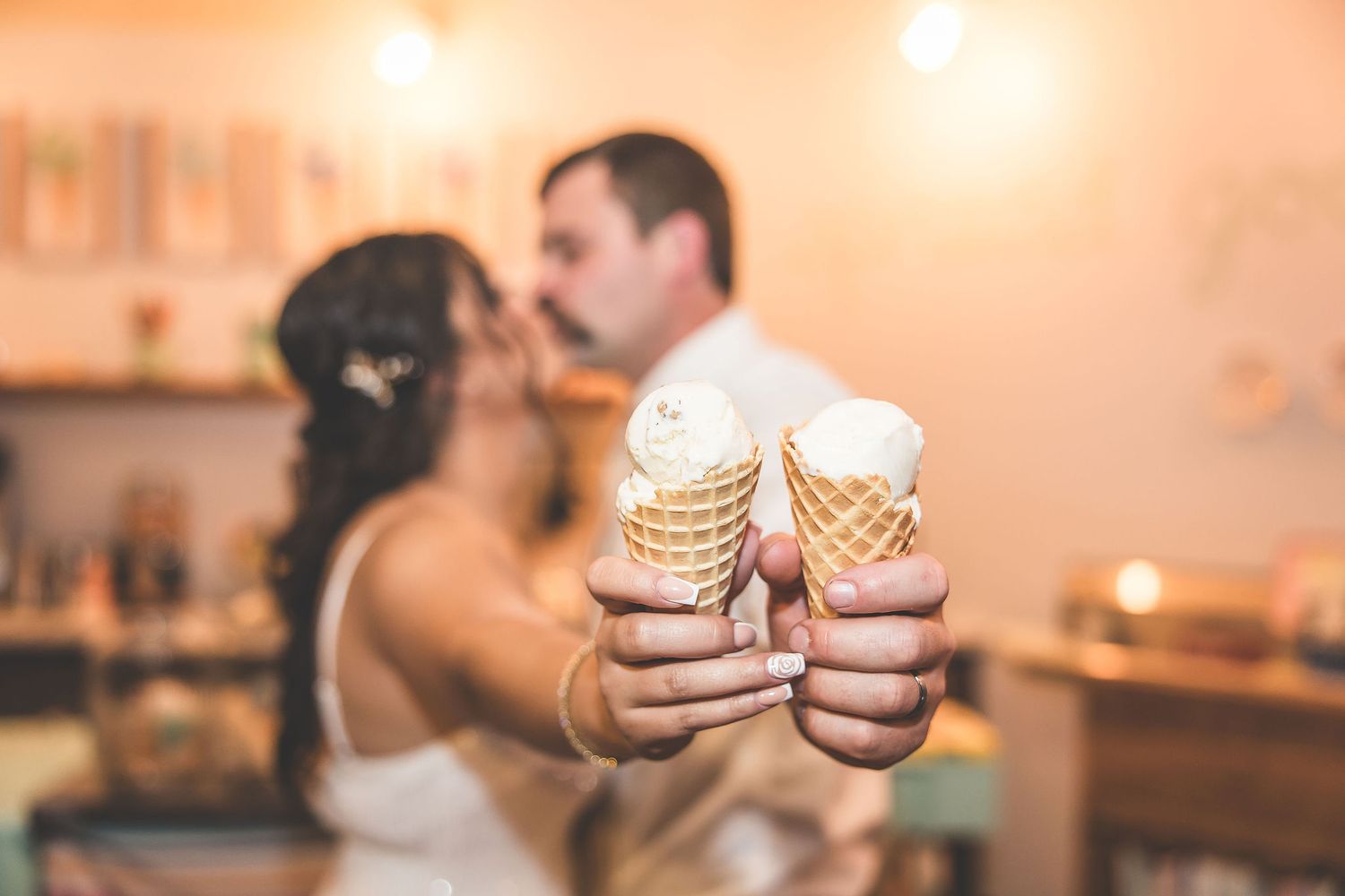 Close-up shots of ice cream cones being enjoyed in a warmly lit ice cream parlor.