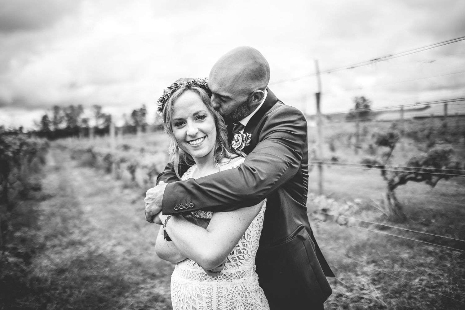 Black and white wedding portraits capture joyful moments between couple in vineyard setting.