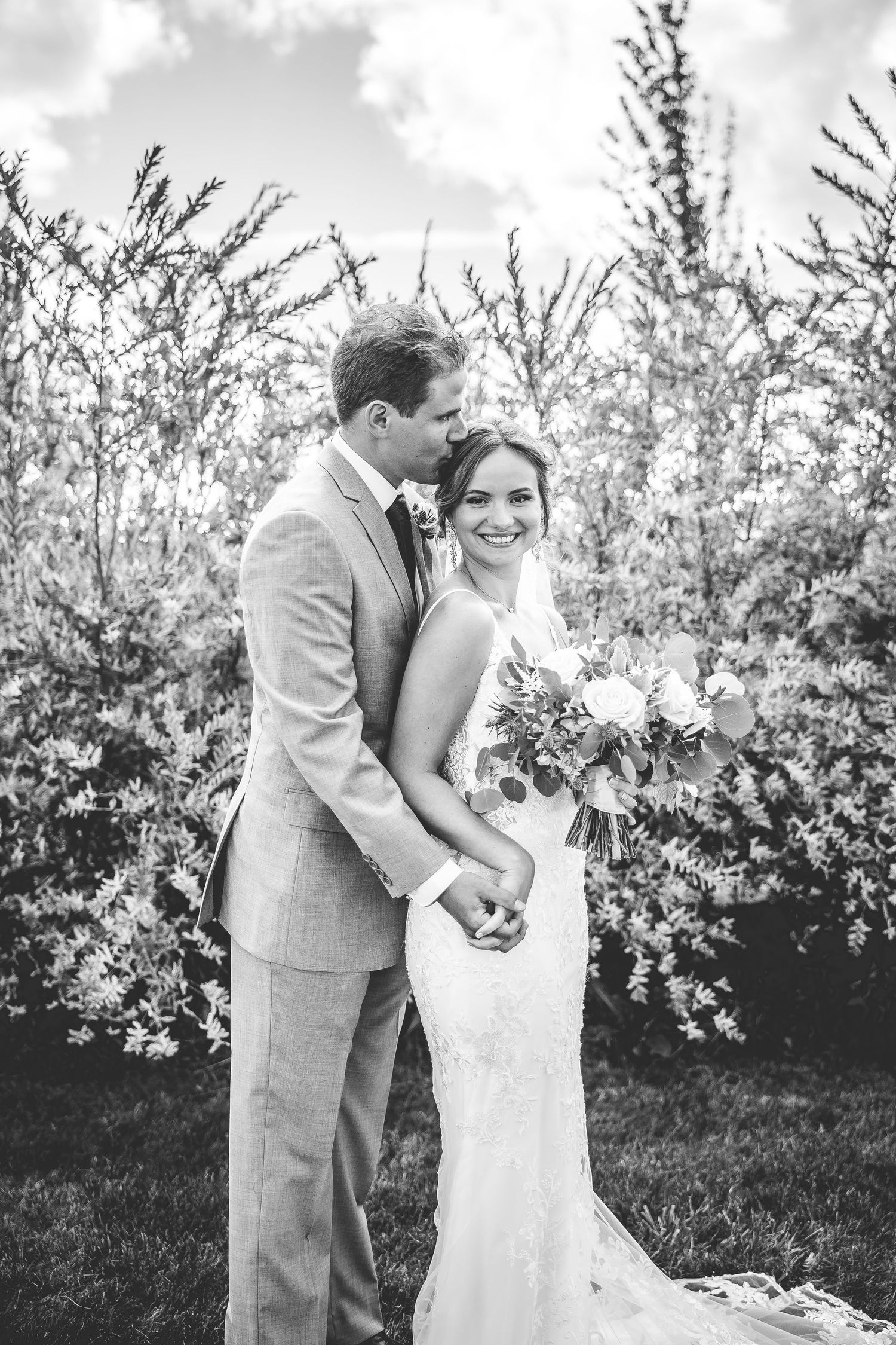 Black and white portrait of couple sharing joyful moment in garden setting.