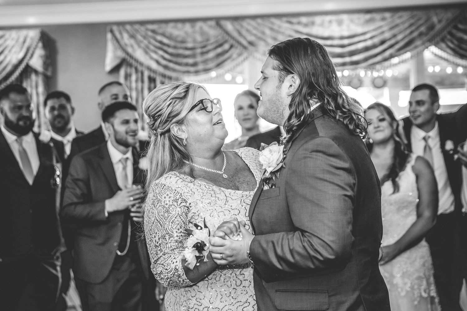 Black and white photo captures joyful moments during wedding reception dancing.