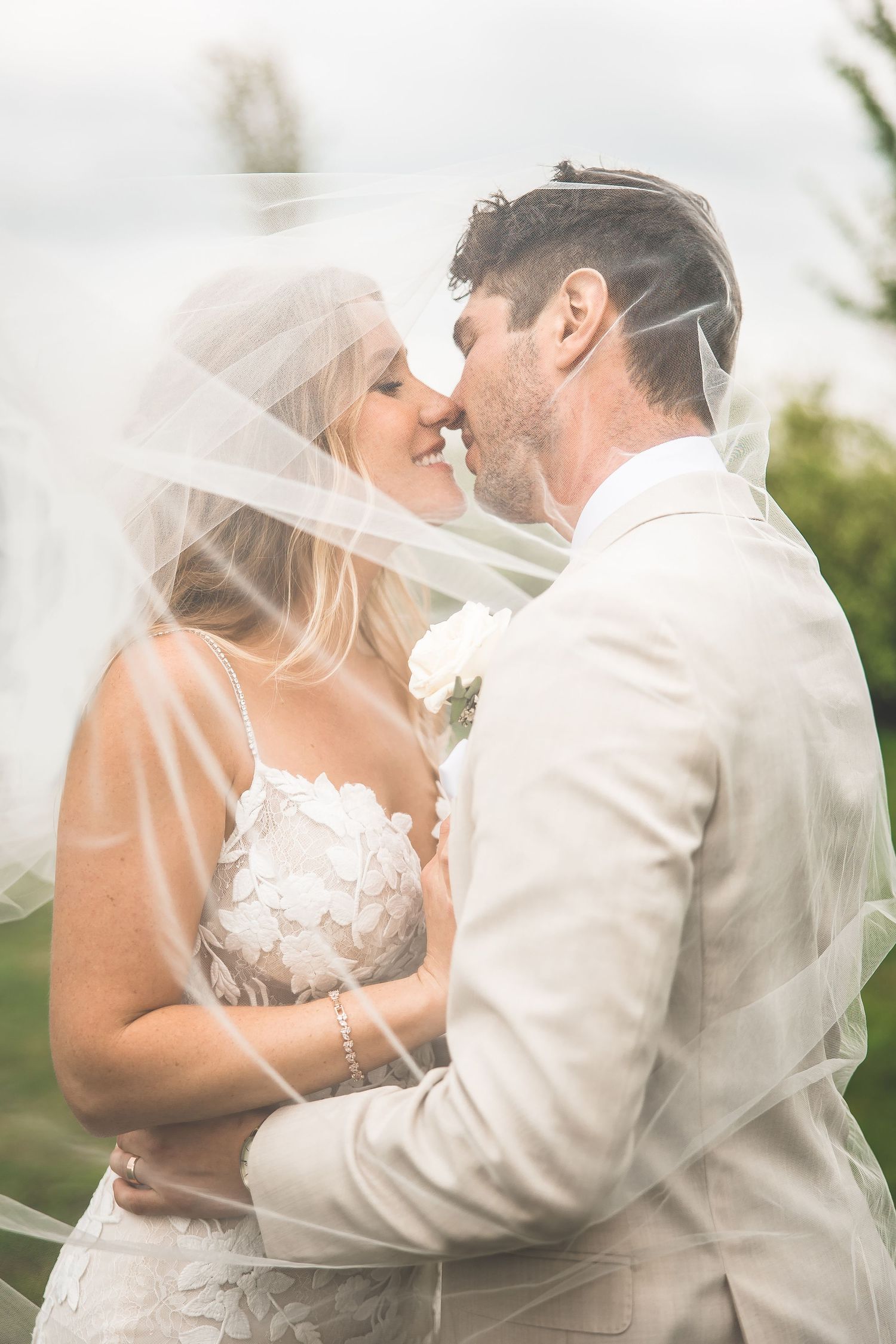 Dreamy wedding portraits with soft focus and flowing veil in outdoor setting.