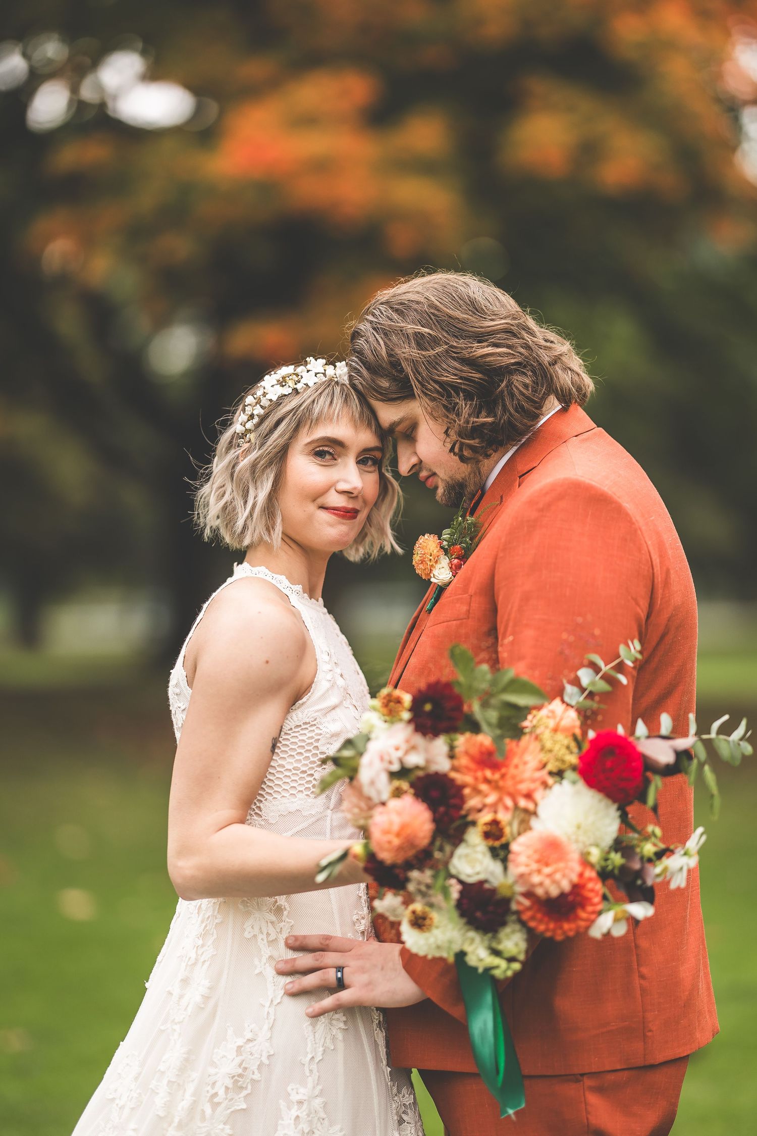 A couple shares intimate moments during their fall wedding with orange trees in the background.