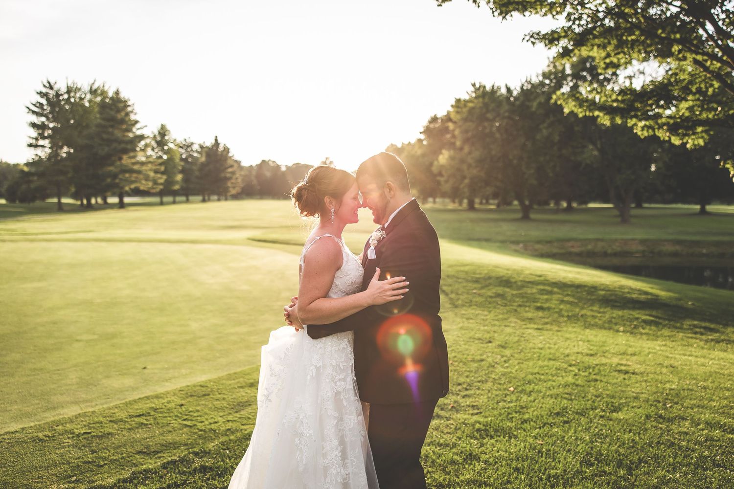 Golden hour wedding portraits on a scenic golf course with dramatic sunlight.