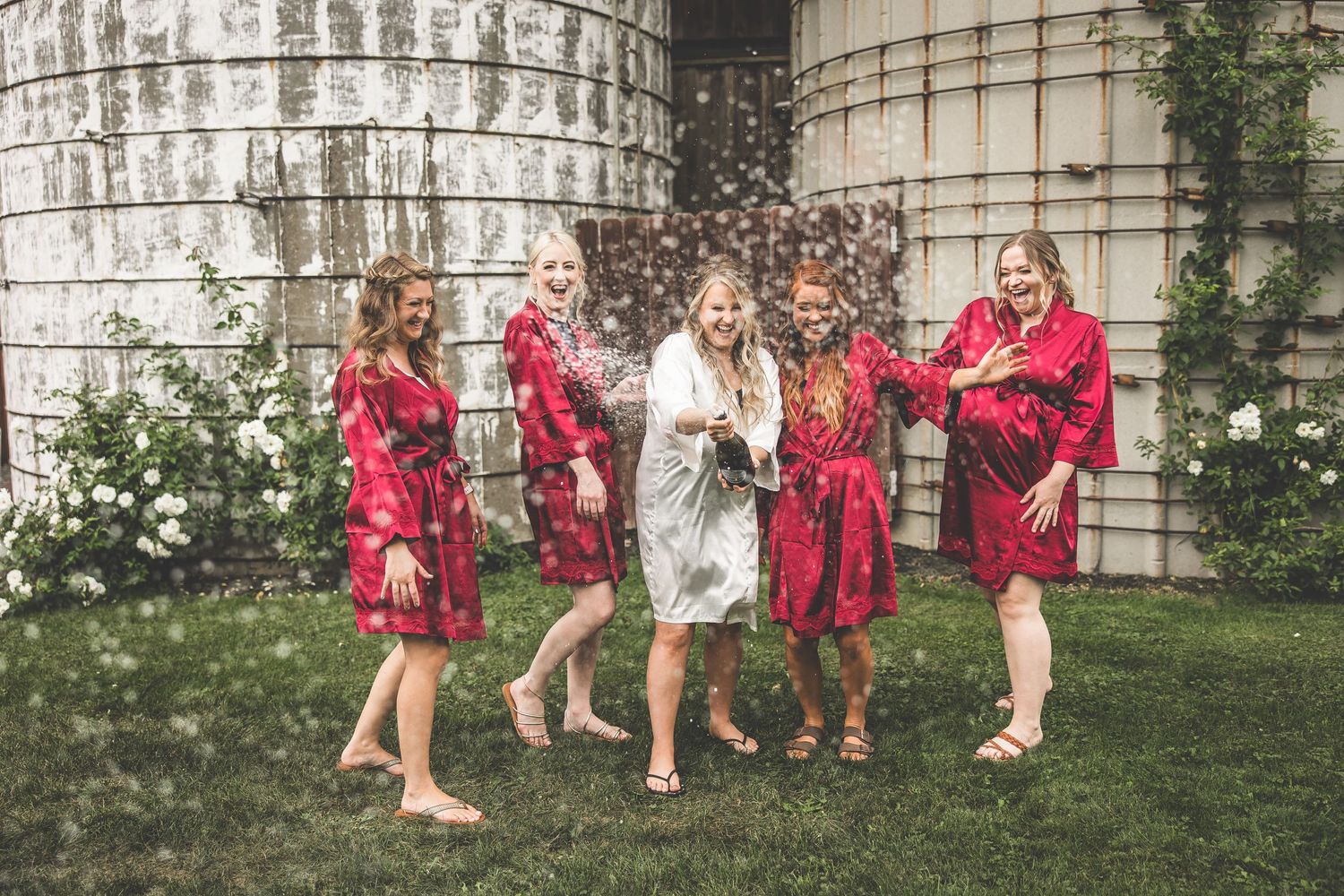 Group celebration in a garden setting with red robes and champagne.