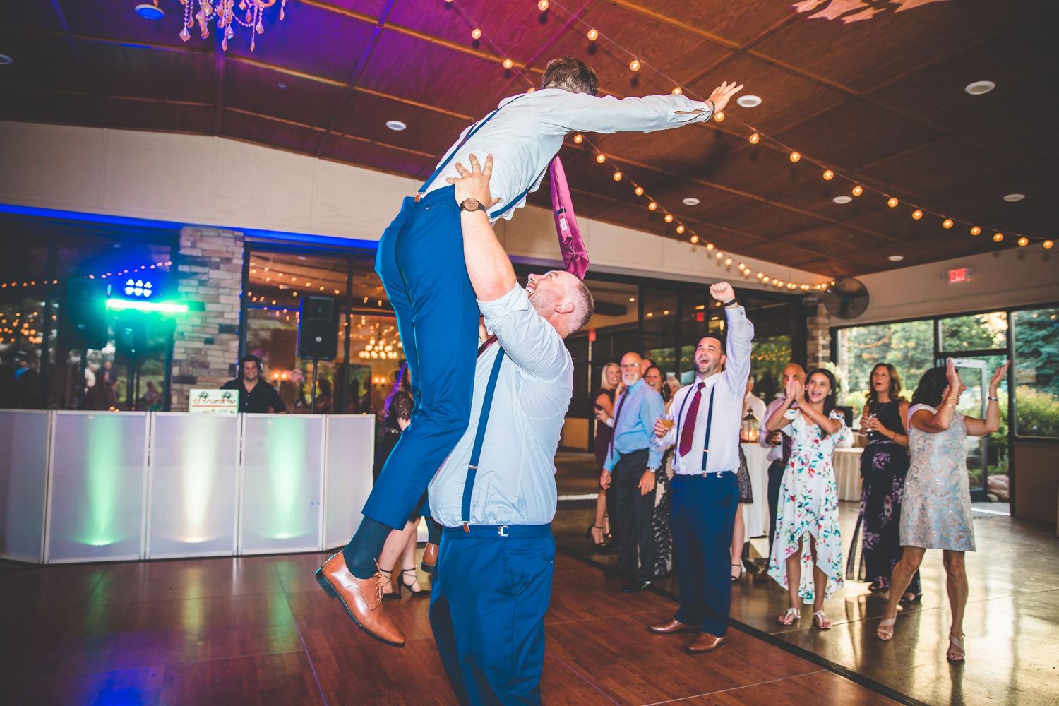 A dramatic dance lift during a wedding reception with guests looking on.