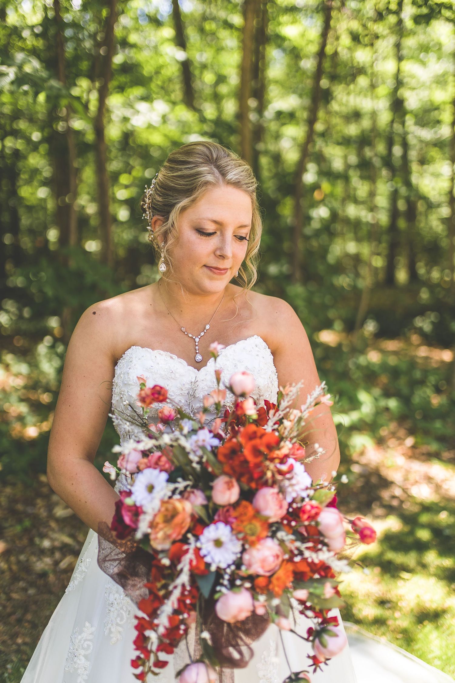 Beautiful bridal bouquet with red and pink flowers in natural forest setting.