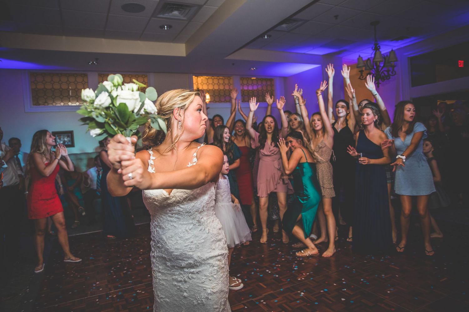 Wedding celebration with guests gathered behind for the traditional bouquet toss moment.