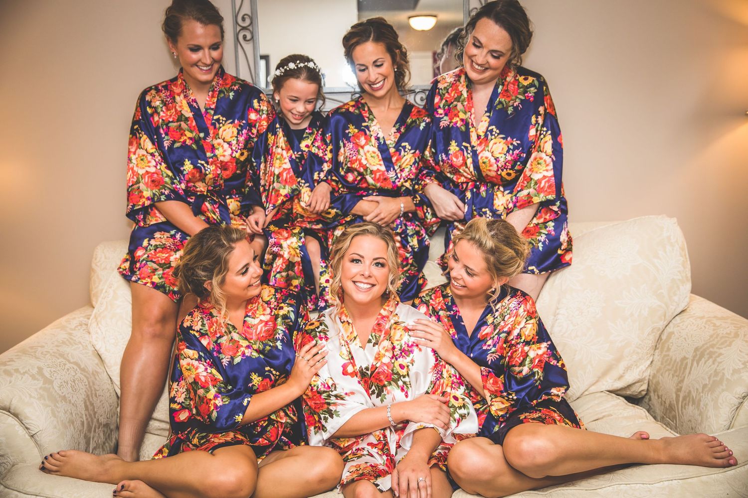 Wedding party relaxing and laughing together on a couch in floral robes.