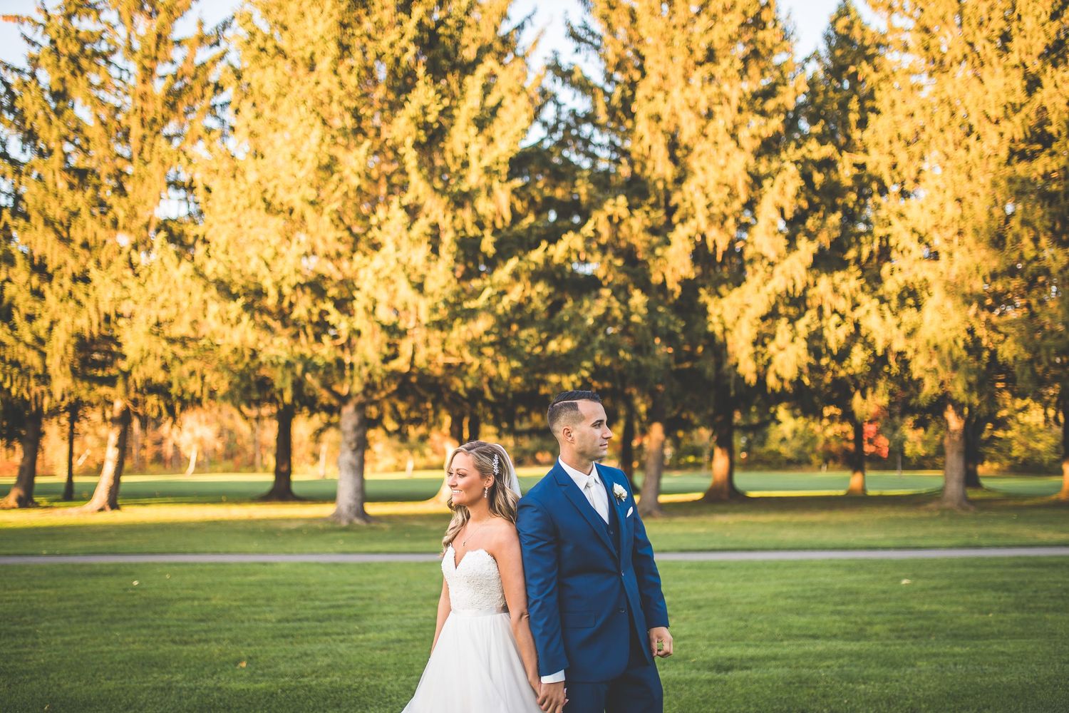 Autumn wedding portrait with golden trees creating stunning backdrop in evening light.