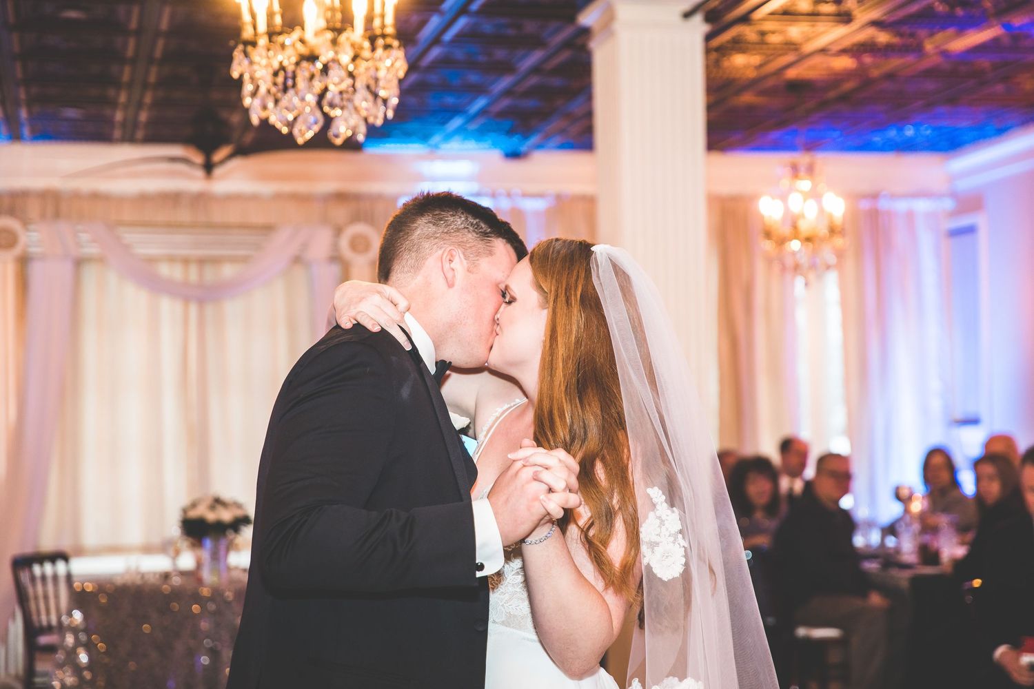Romantic dance moment captured in an ornate ballroom with dramatic purple lighting.