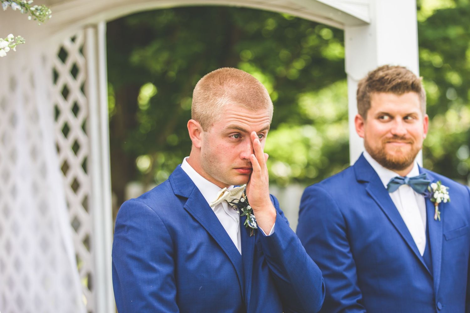 Emotional moment captured during outdoor wedding ceremony at white lattice gazebo.