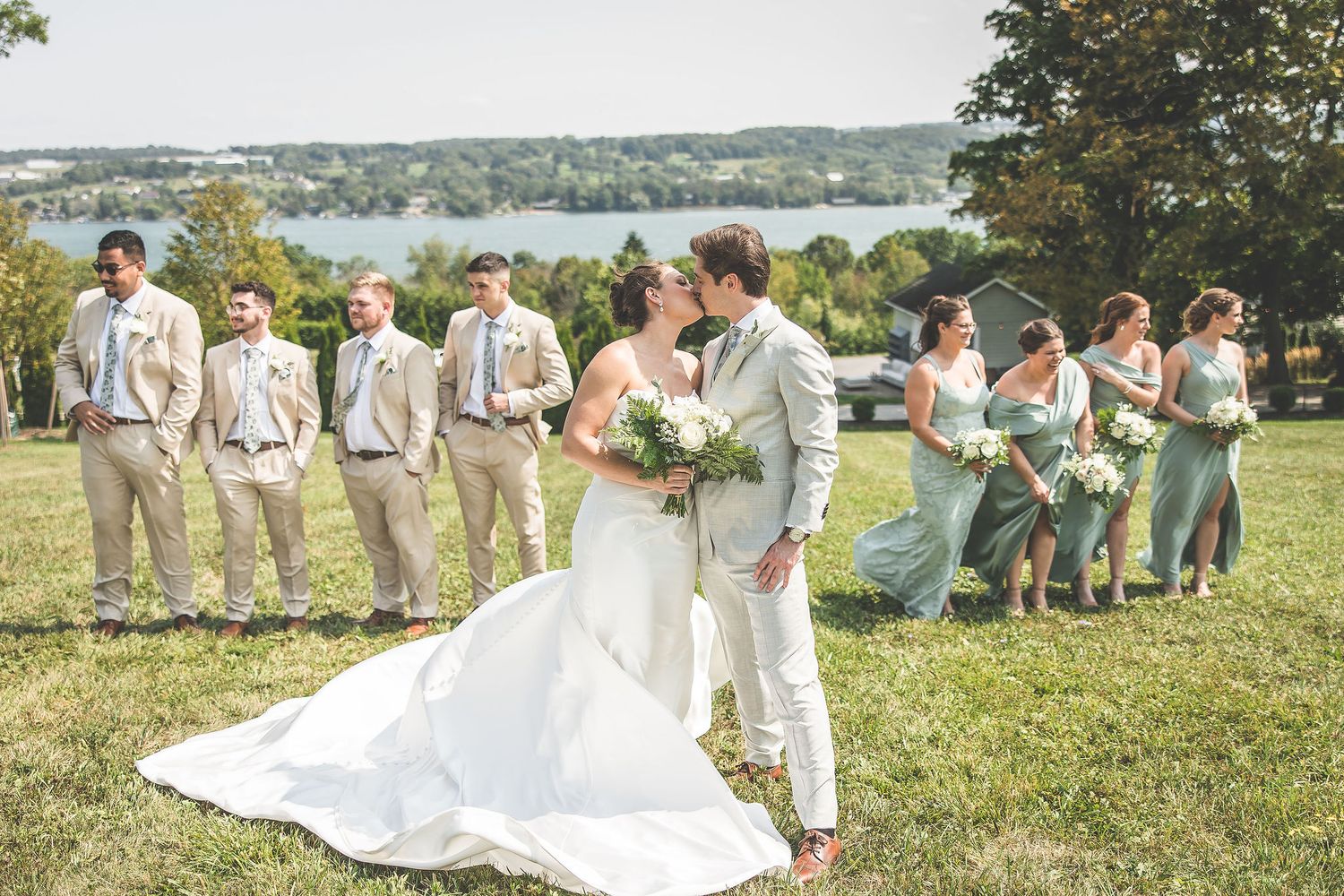 Wedding group photo session on a hilltop with water views in the background.
