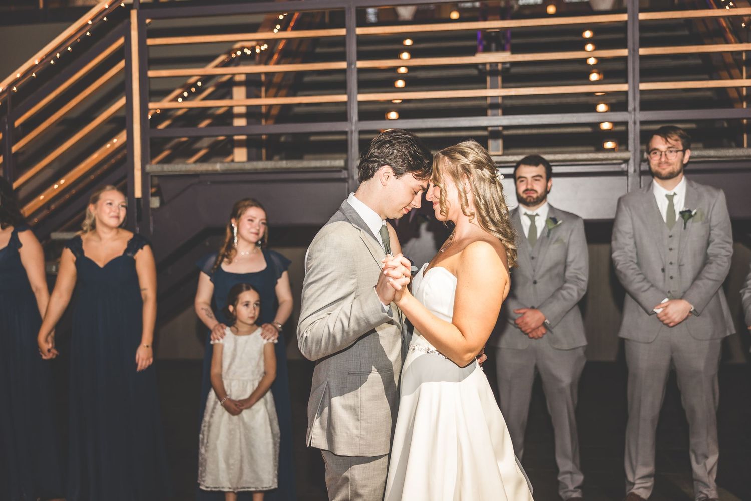 Wedding celebration with groomsmen in grey suits and rustic venue decor.
