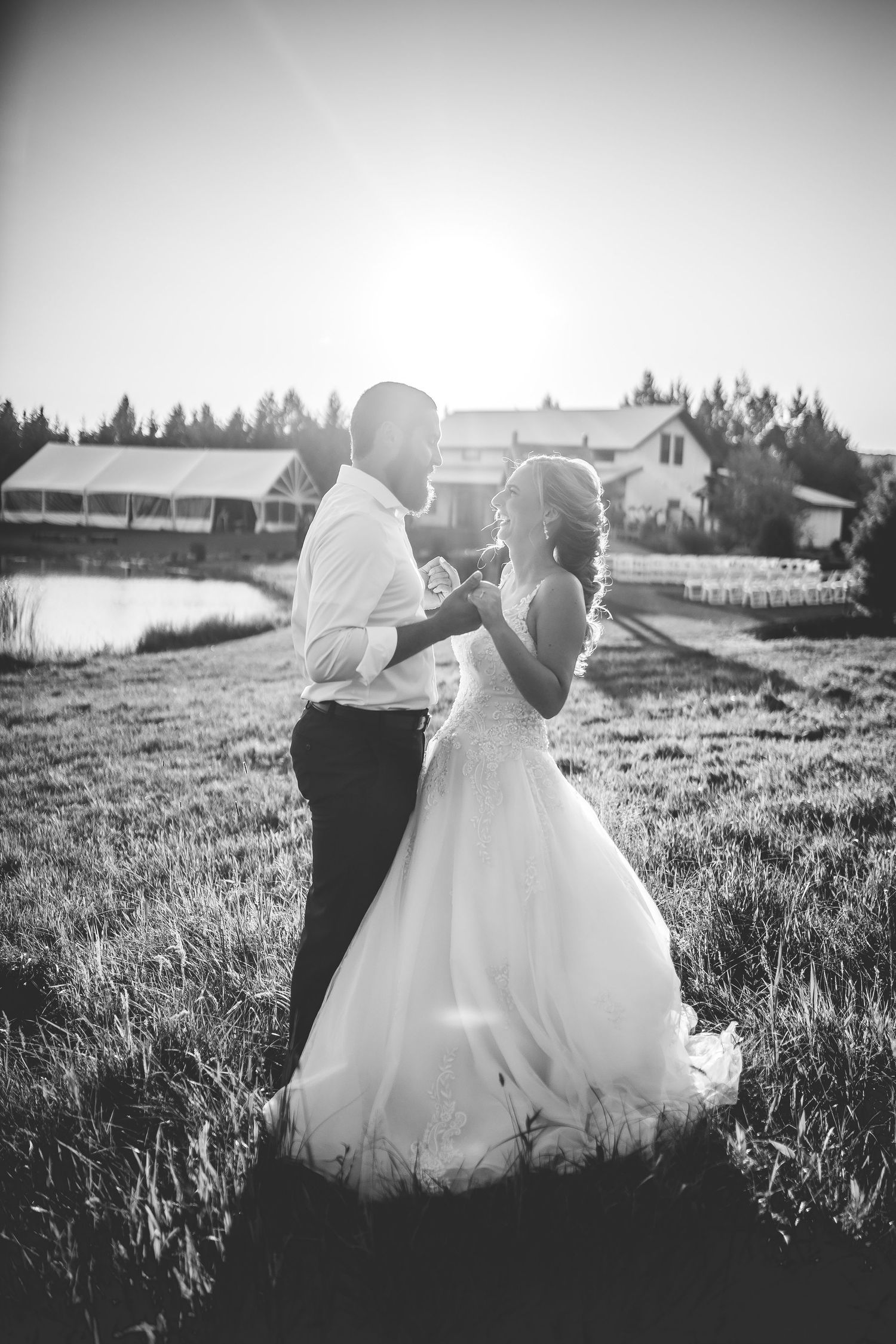 Black and white portrait of couple dancing in a meadow at sunset.