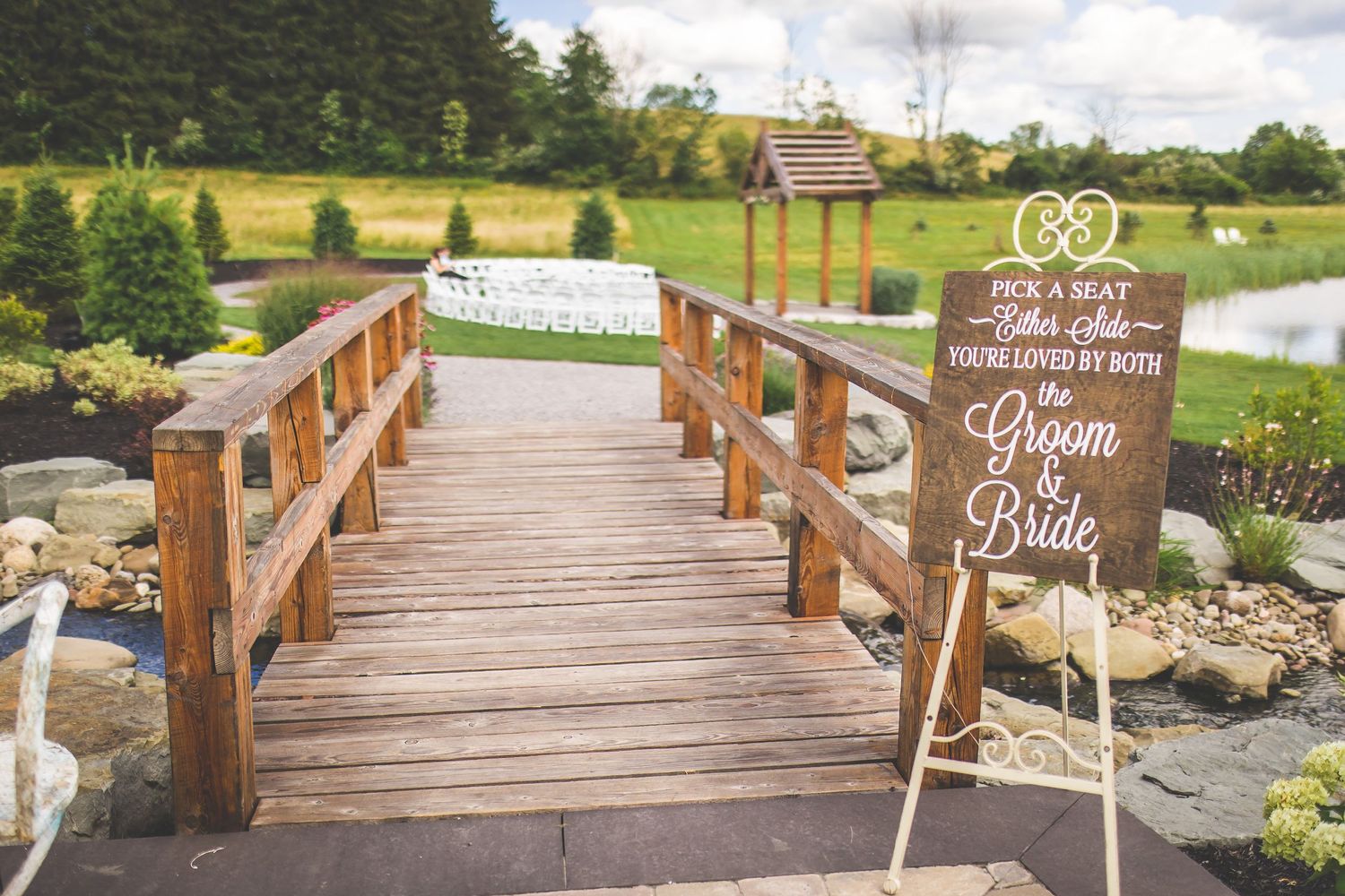 Rustic wooden bridge decorated with wedding signs and floral arrangements.