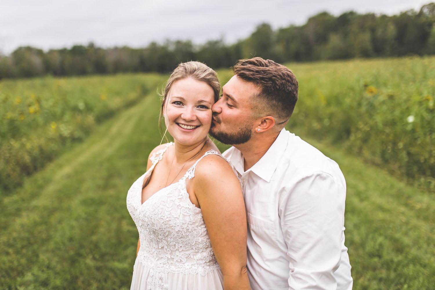 Couple laughing together in a sunlit meadow with yellow flowers.