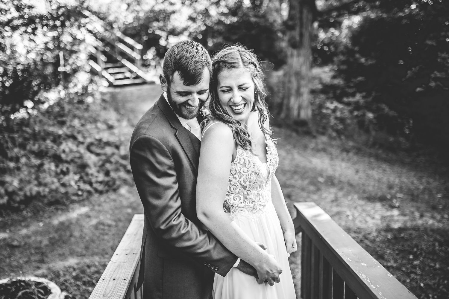 A black and white portrait of a couple sharing an intimate moment on a wooden deck.