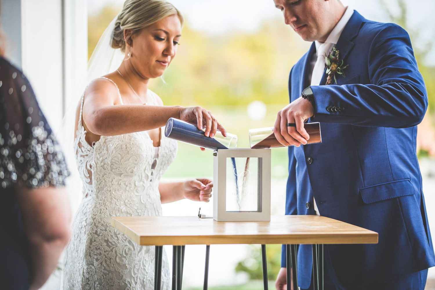 Couple performs unity ceremony ritual at modern wedding venue with natural lighting.