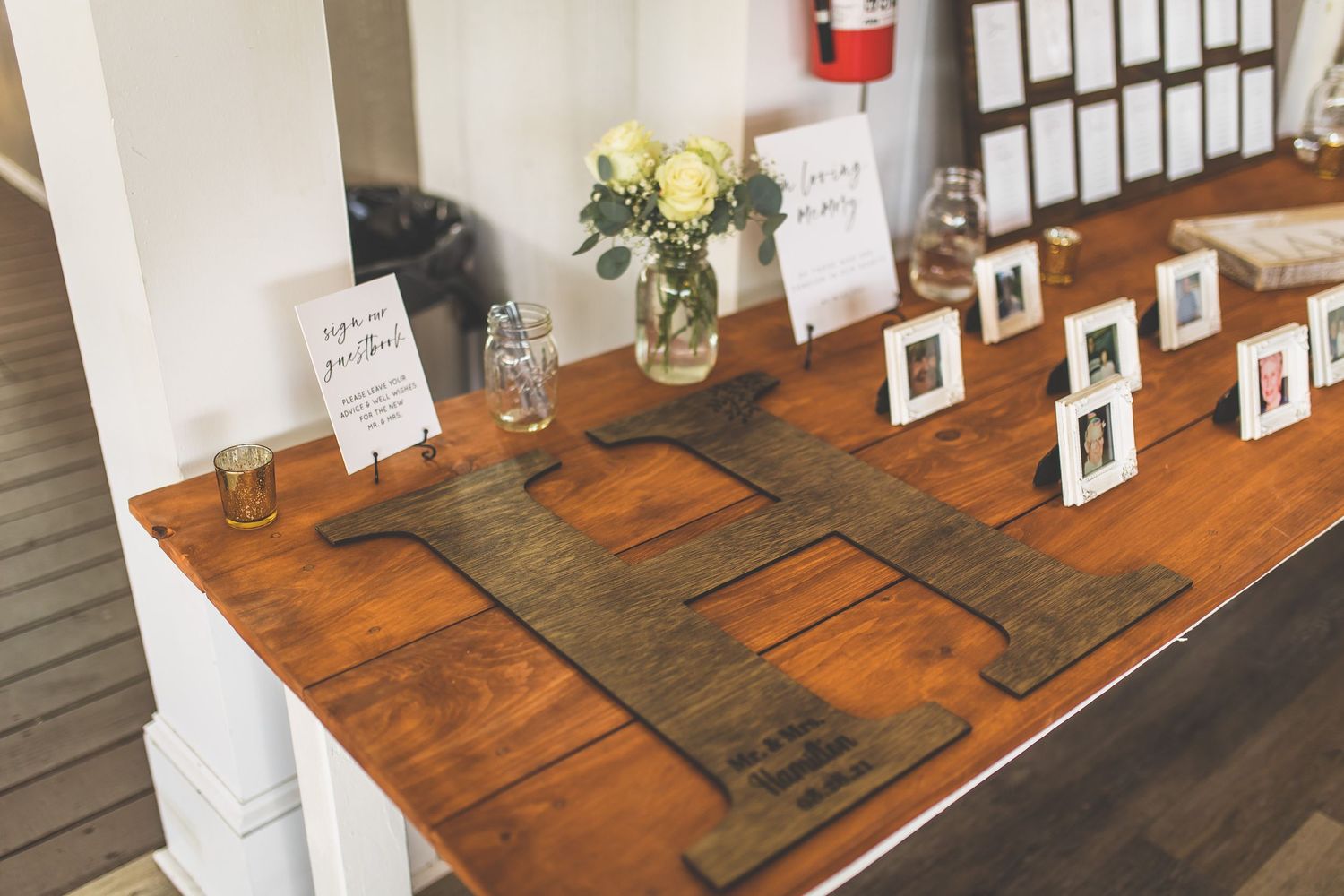 Wedding reception table decor with wooden signs and small floral arrangements in glass vases.