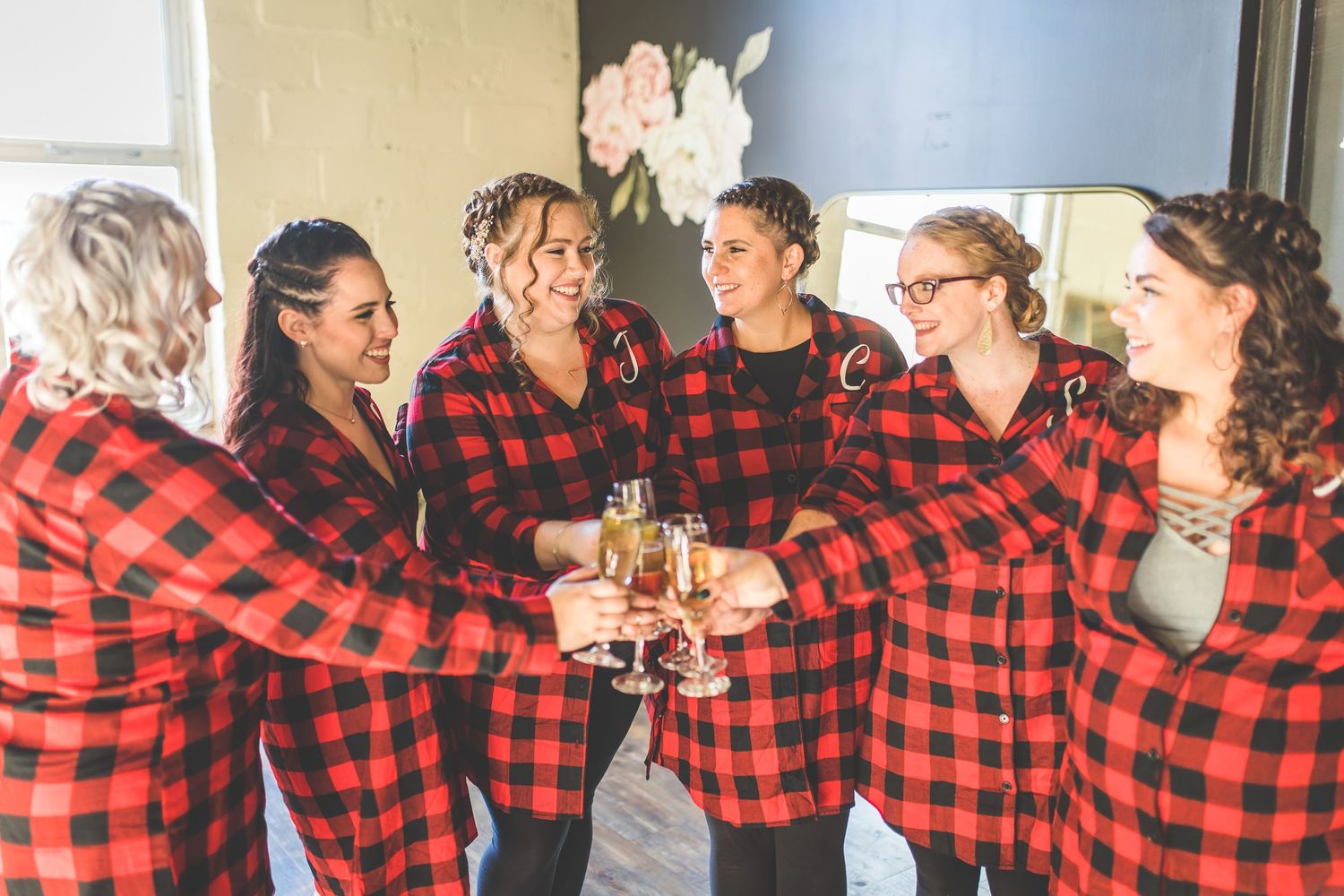 People in coordinated red buffalo plaid shirts posing together in casual setting.