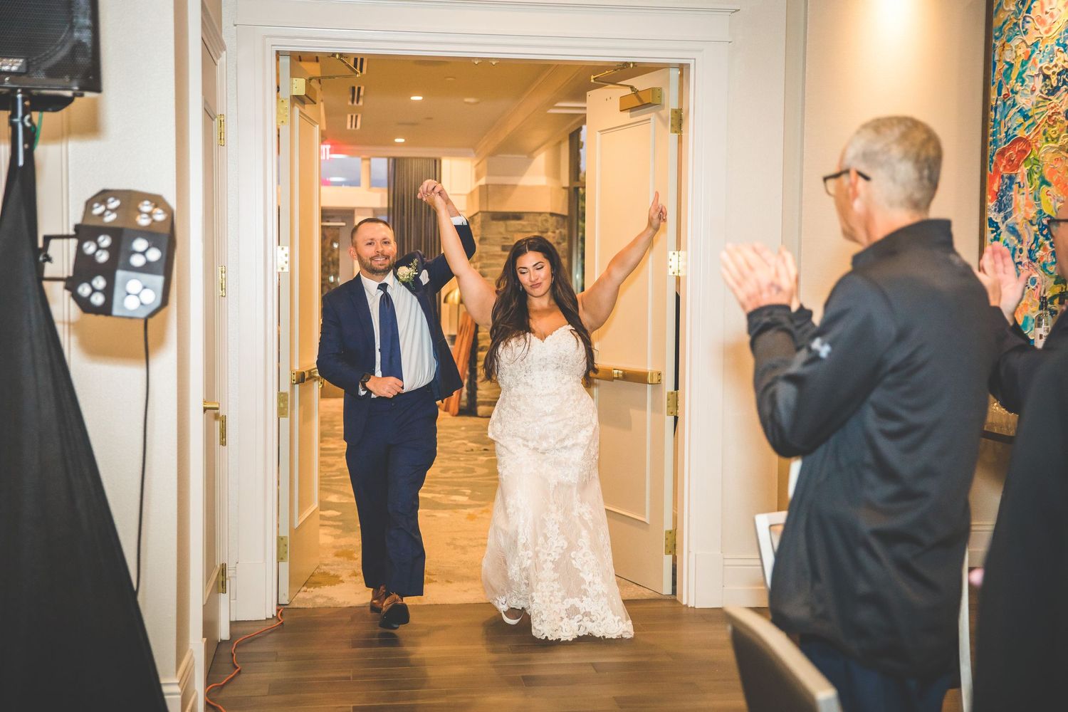 Wedding party walking through an elegant hallway with white walls and colorful artwork.