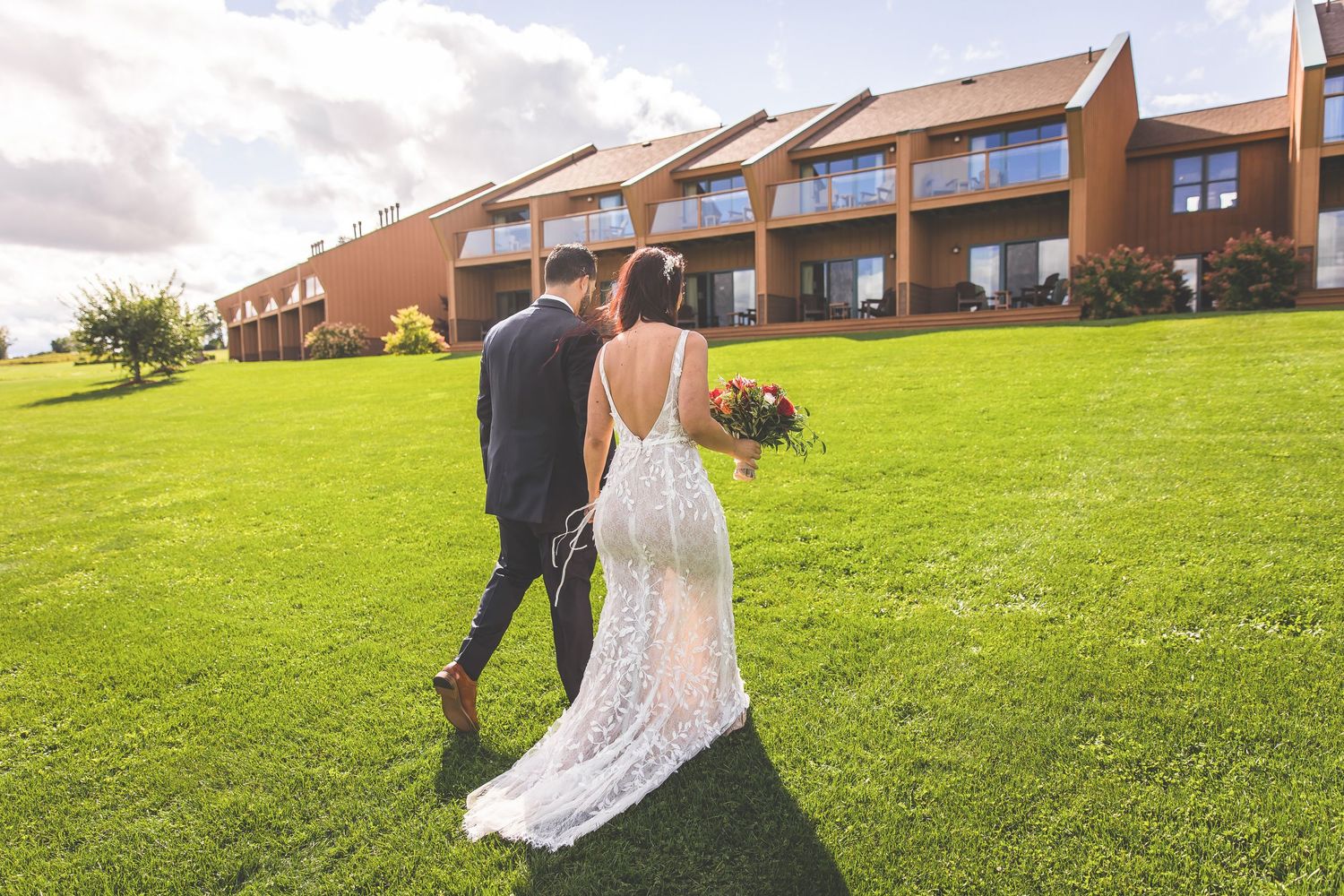 Outdoor wedding venue overlooking rolling hills with white chairs and decorative arch.