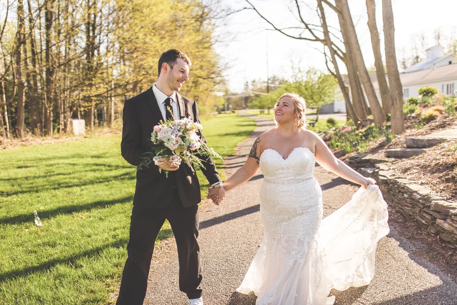Newlyweds sharing joyful moments outdoors in a sunlit garden setting.
