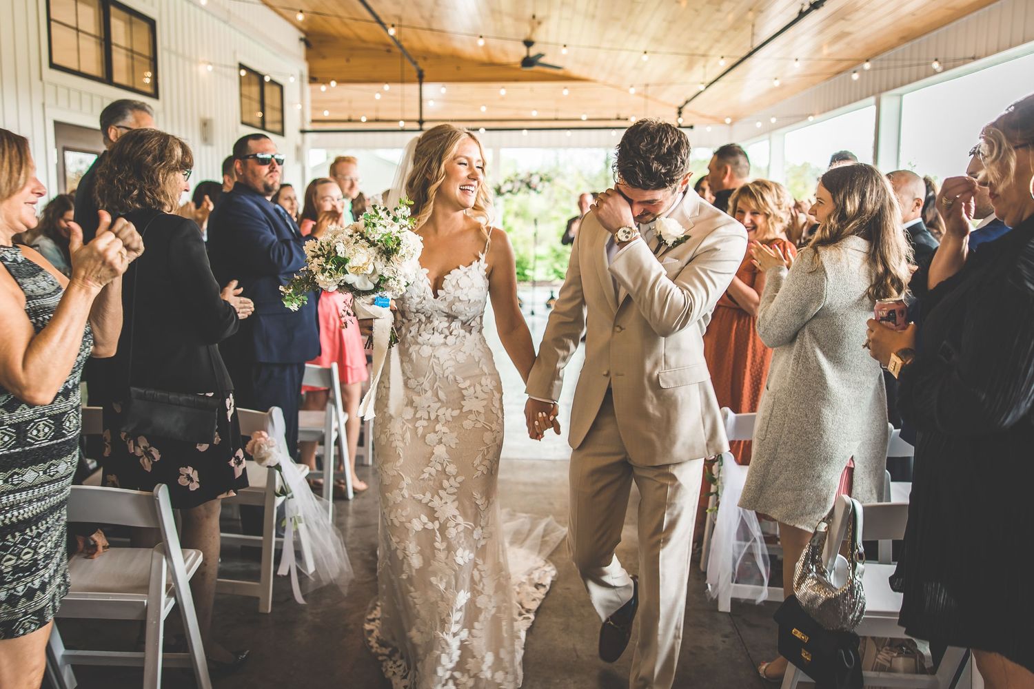 Wedding celebration with guests cheering as couple dances in rustic indoor venue.