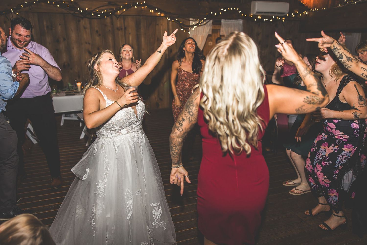 Wedding reception dance party with guests enjoying themselves under ambient lighting.