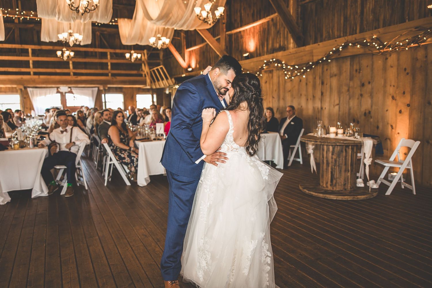 Couple sharing an intimate dance moment in a beautifully lit rustic barn venue.