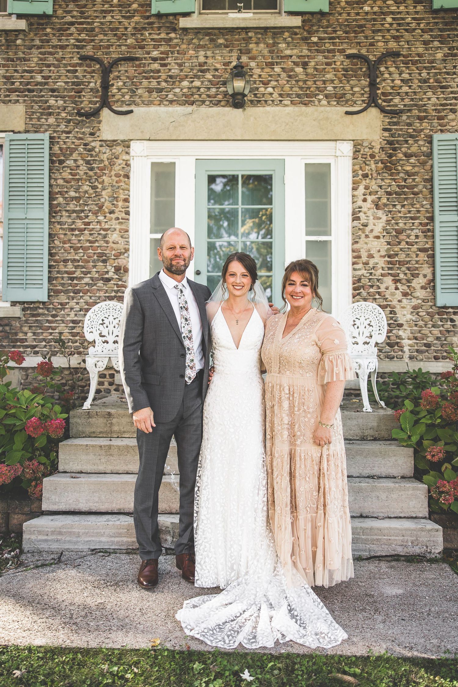 A formal portrait on stone steps of a historic building with elegant wedding party attire.