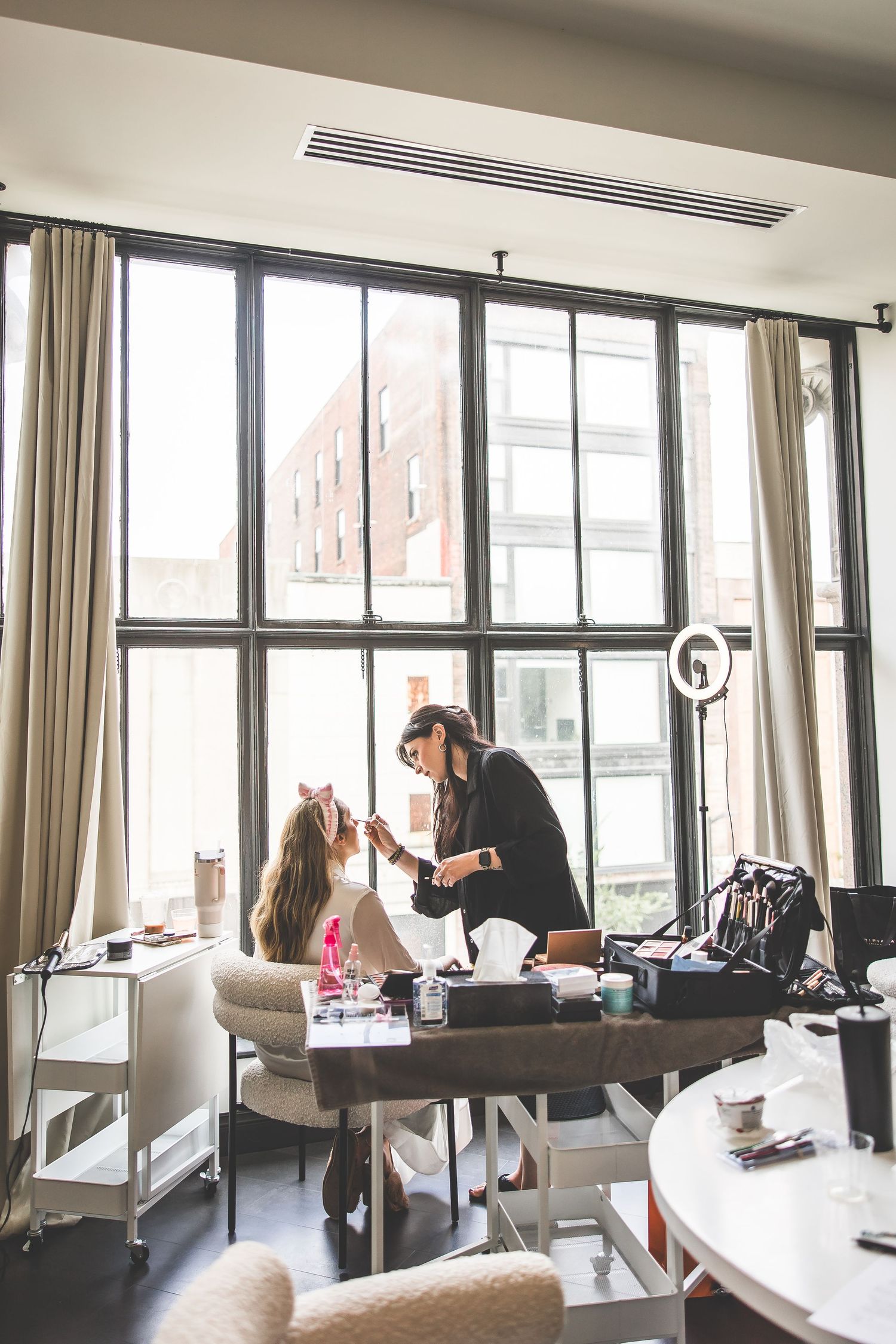 Bright modern room with large windows and white furniture where wedding preparations are taking place.