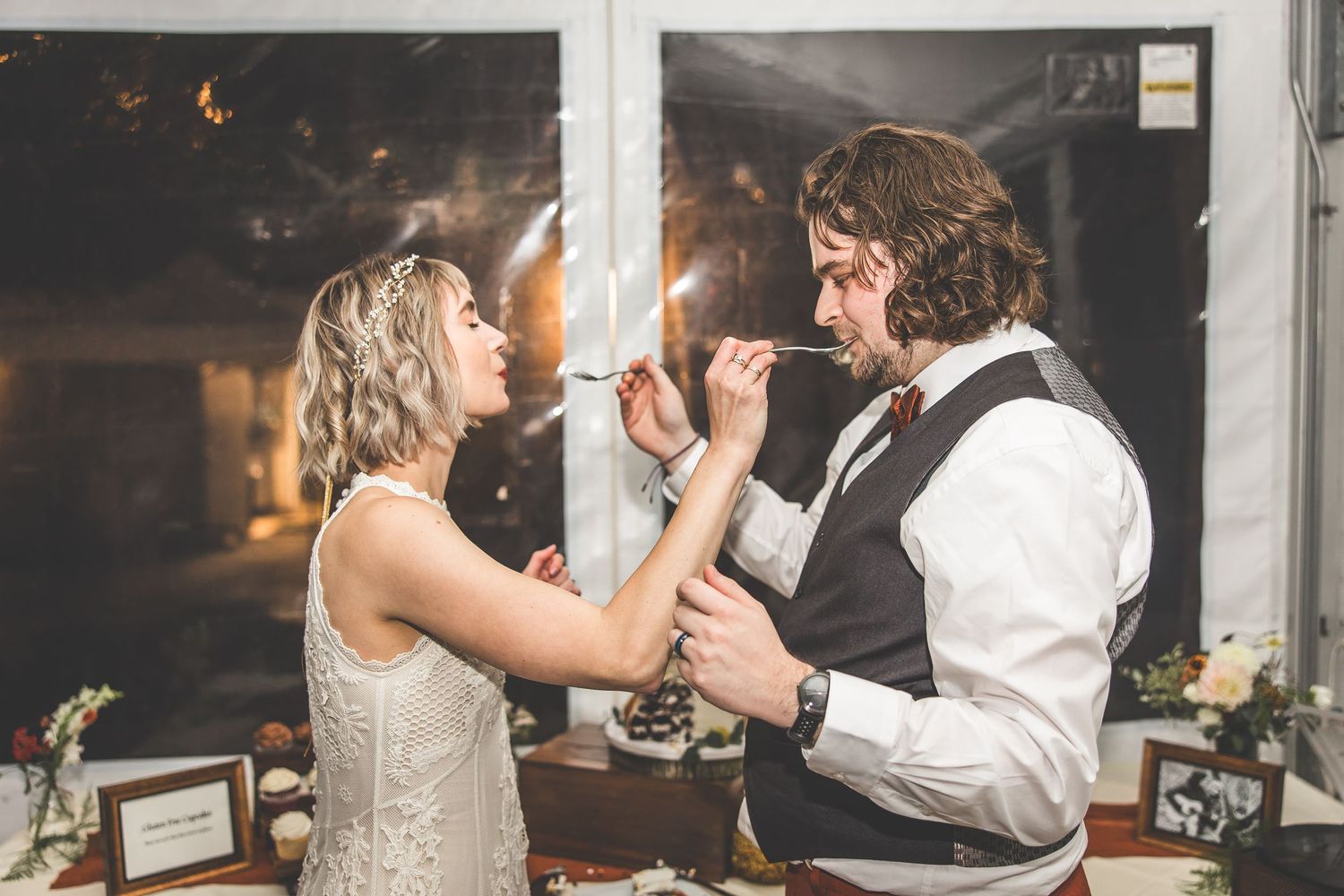 Wedding reception guests dancing and celebrating on a dimly lit dance floor with string lights overhead.