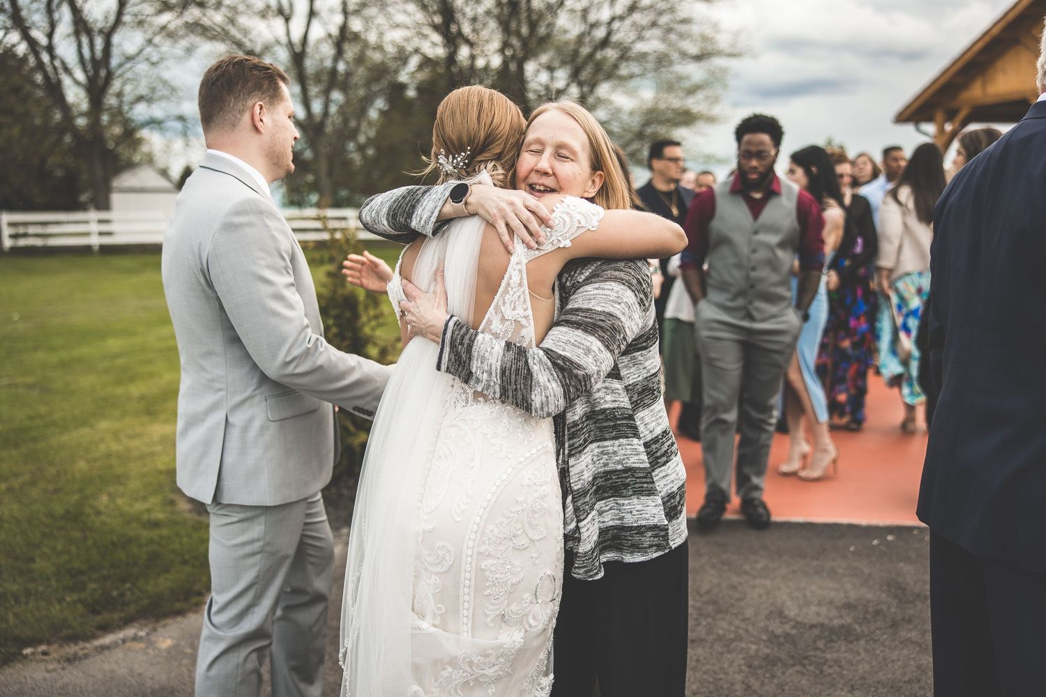 Wedding guests congratulating couple during outdoor reception at rustic venue.