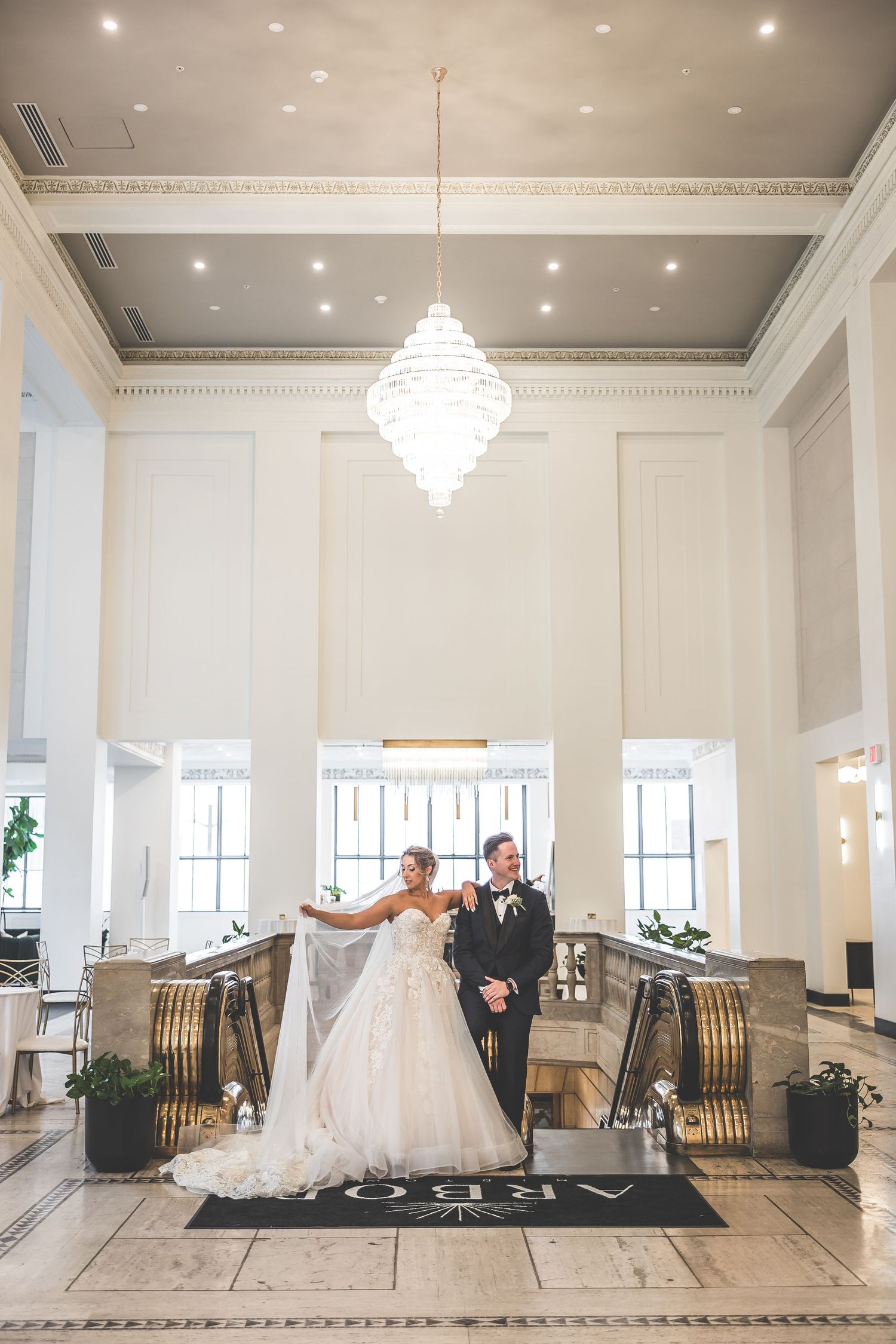 Elegant wedding venue with crystal chandeliers and white decor in a spacious ballroom.
