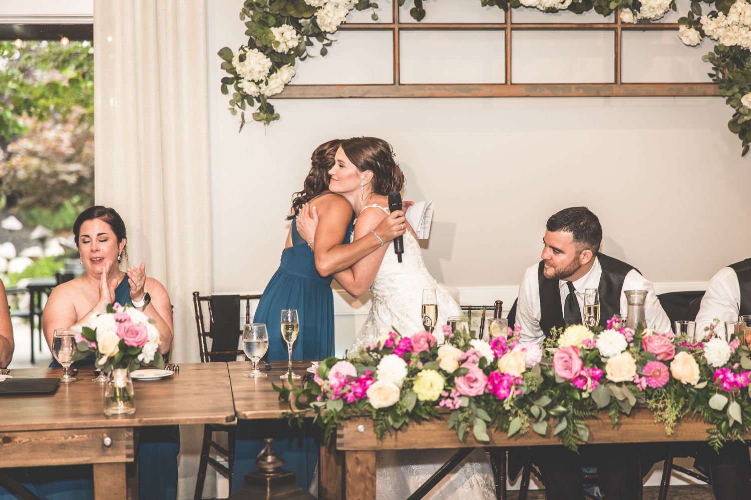 Wedding reception space with rustic wooden head table and floral decorations.